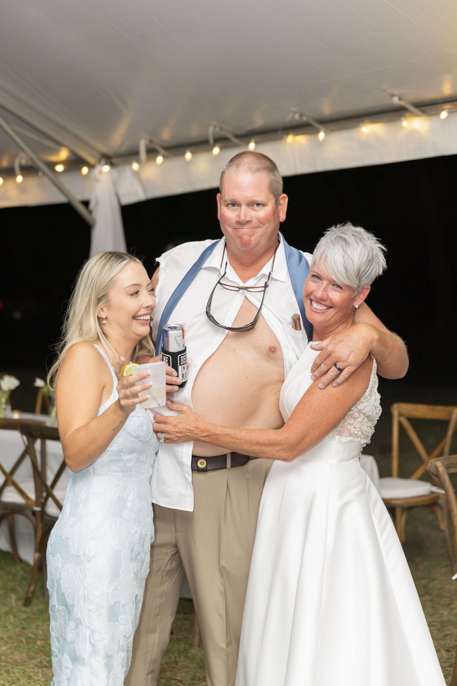 Wedding celebration with guests laughing and dancing together under a tent.