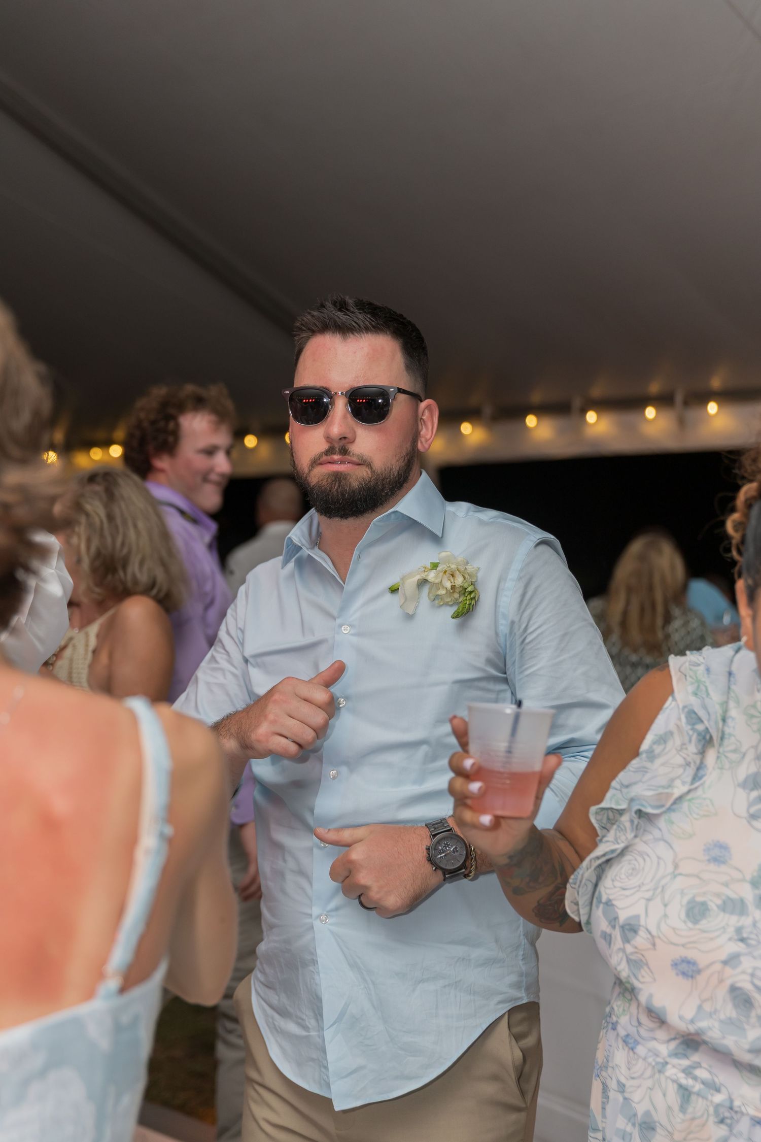 Wedding guests dancing and enjoying themselves under a reception tent at night.