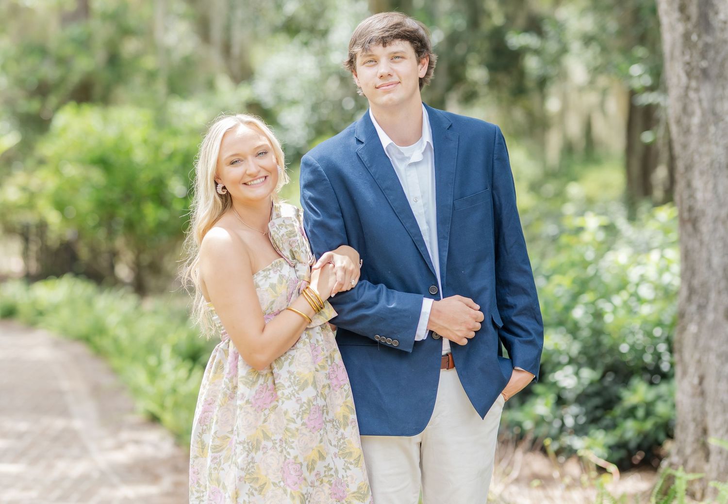 A couple shares romantic moments while walking along a garden path surrounded by greenery.