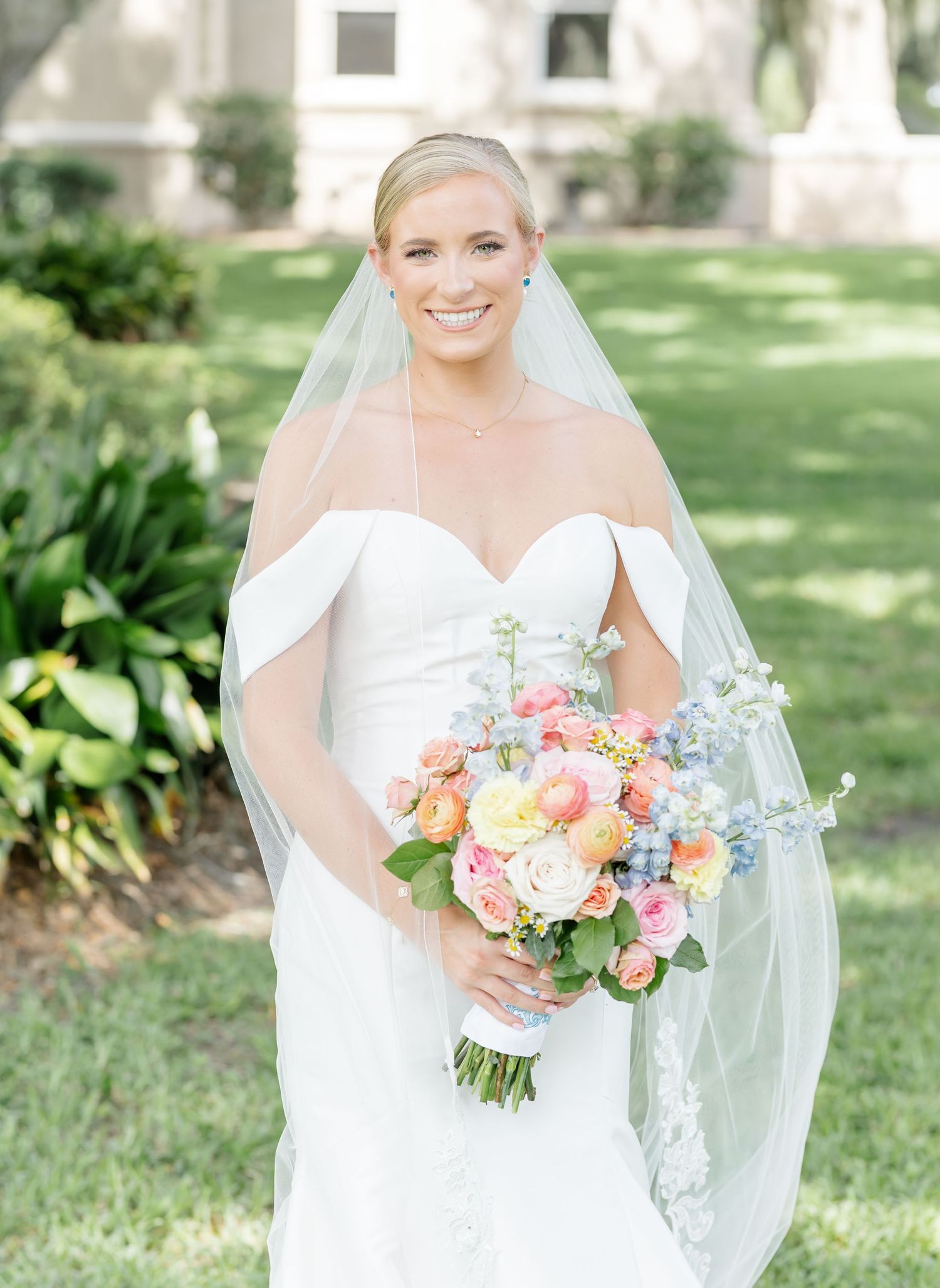 Three photos of a bride in a white dress holding colorful coral and pink bouquets in an outdoor garden setting.