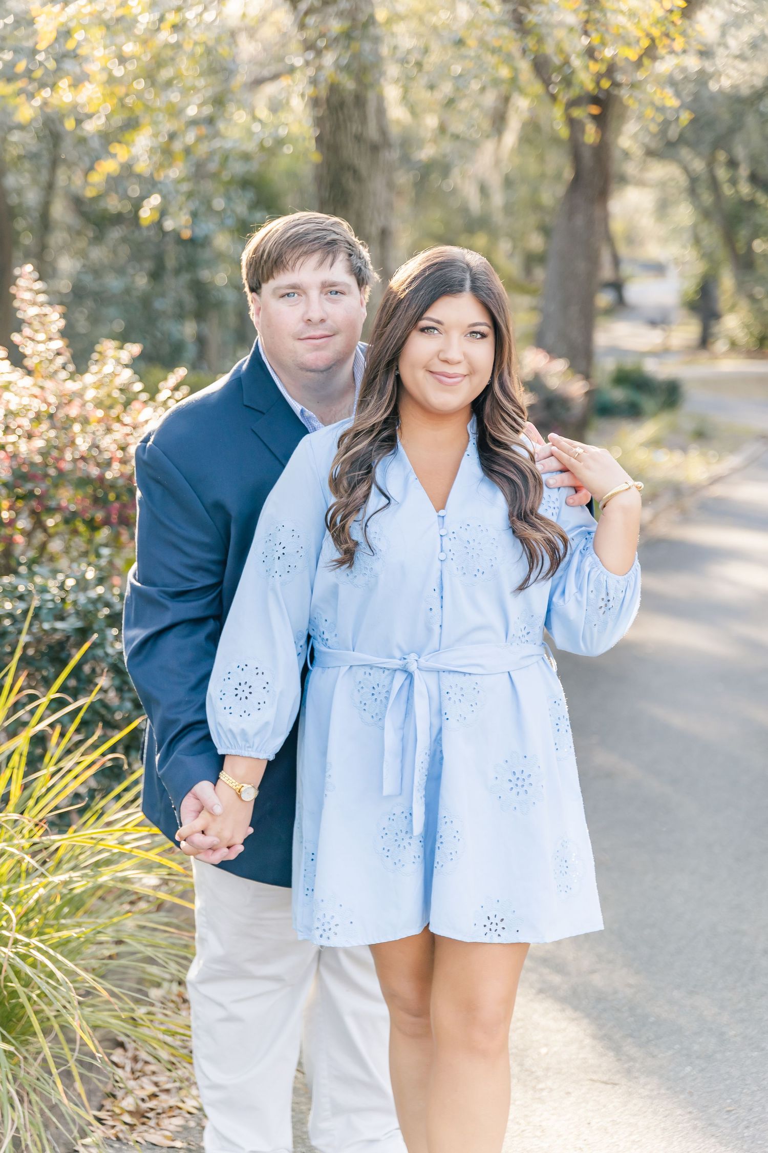 A spring engagement photo featuring a couple in matching blue outfits on a sunlit garden path.