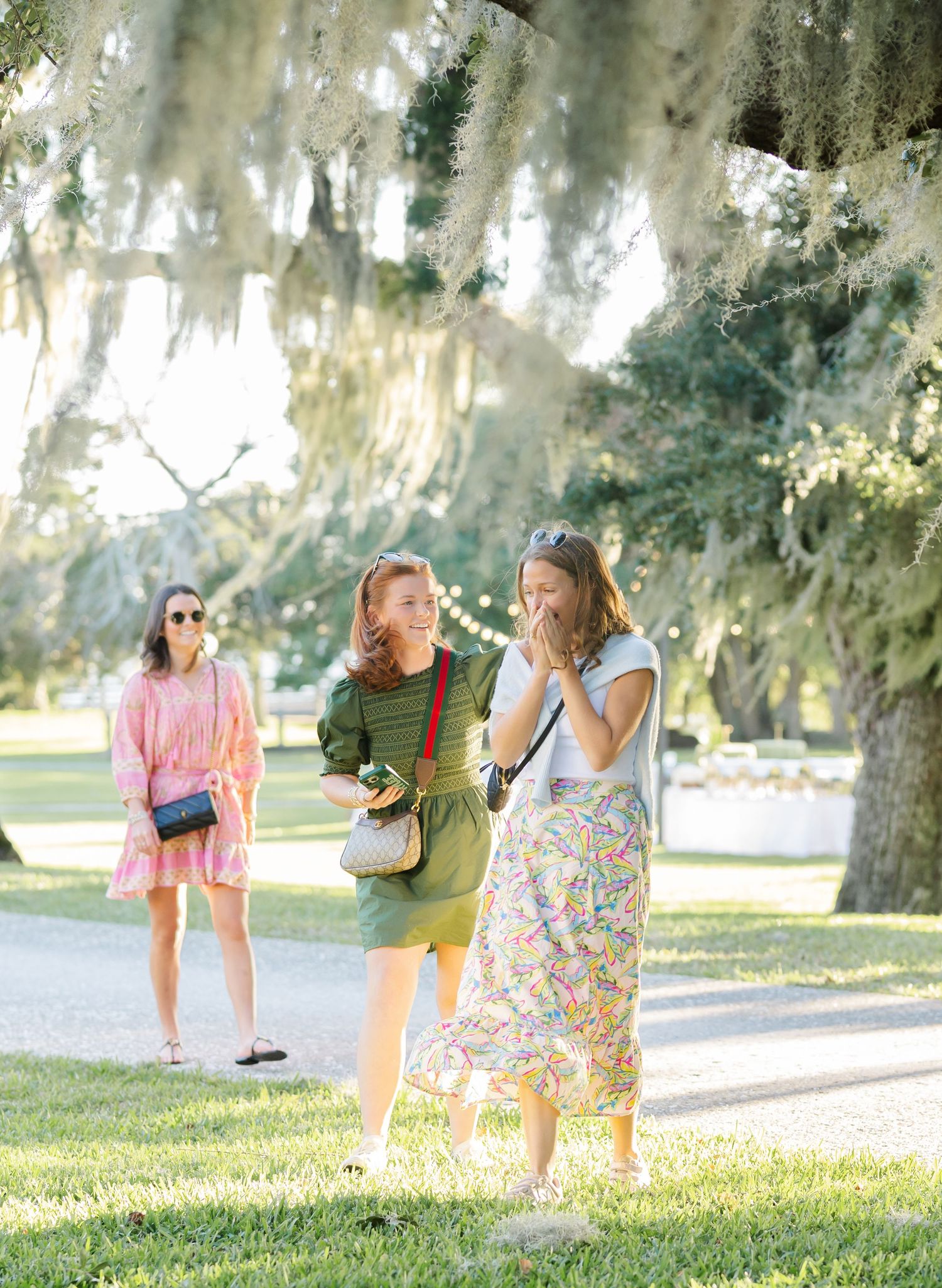 A playful couple enjoys a fun moment together on a grassy lawn with Spanish moss draped trees in the background.