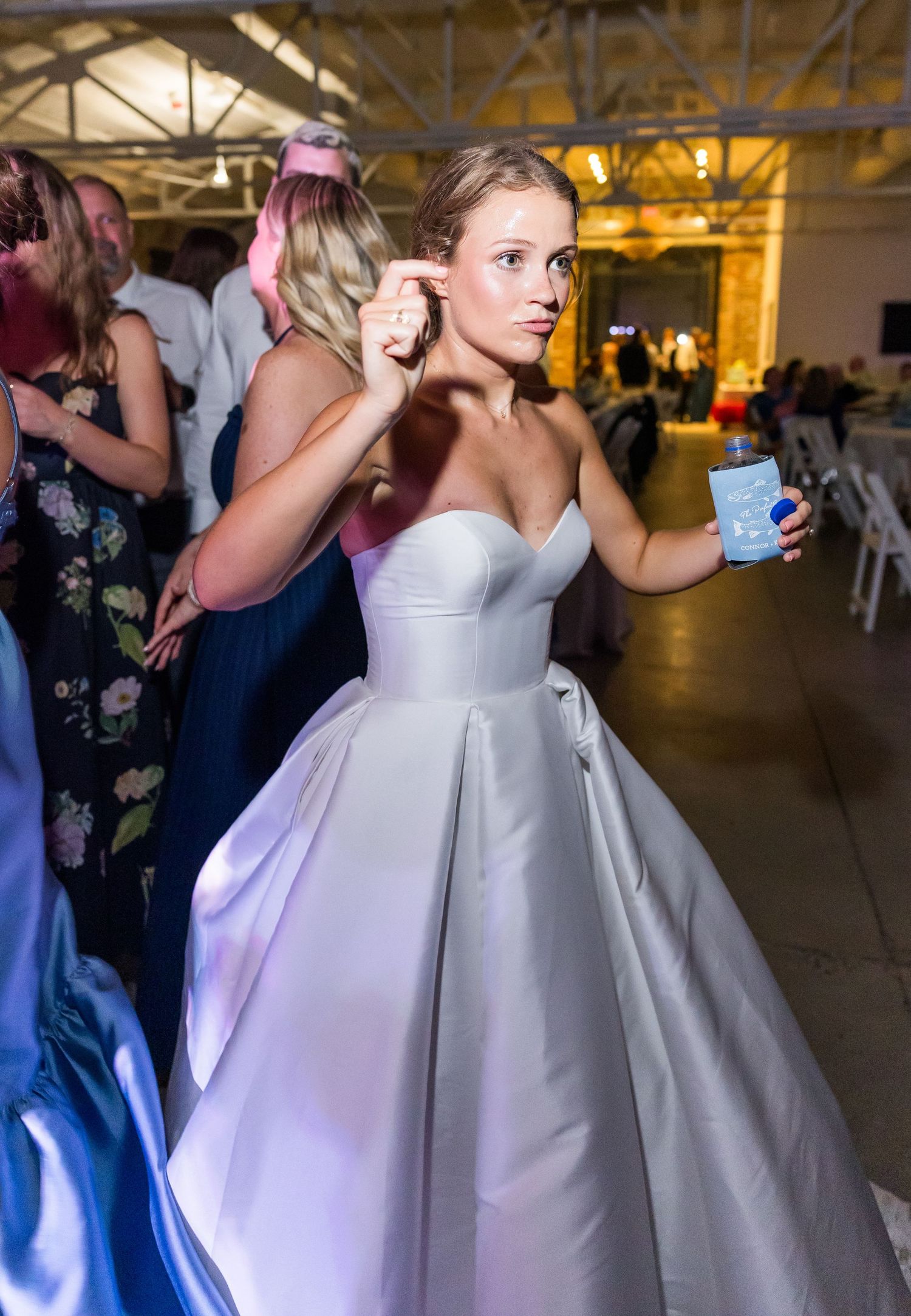 Bride in strapless ball gown dances and enjoys a drink at her festive wedding reception celebration.