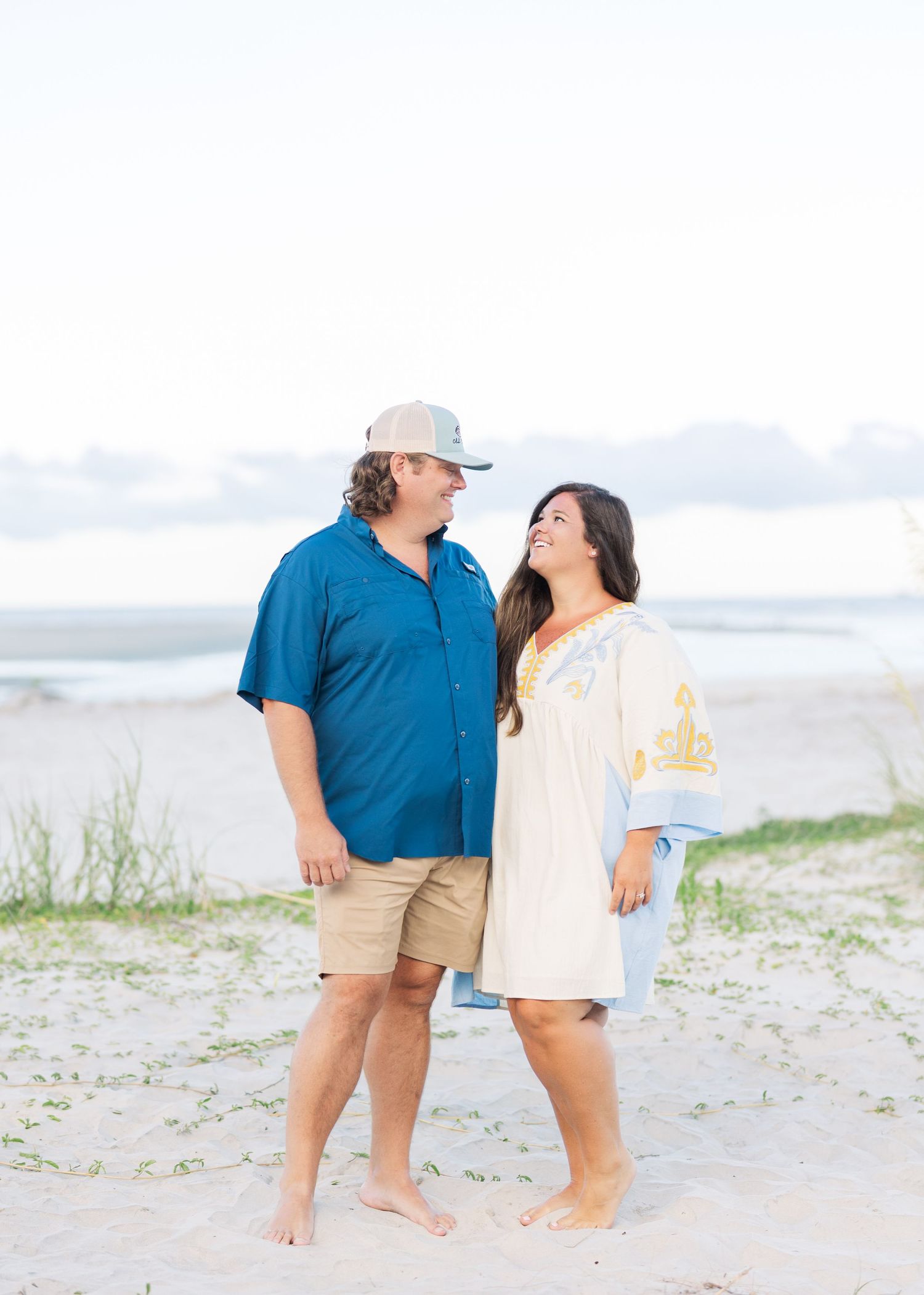 A couple shares a romantic moment while standing barefoot on the beach.