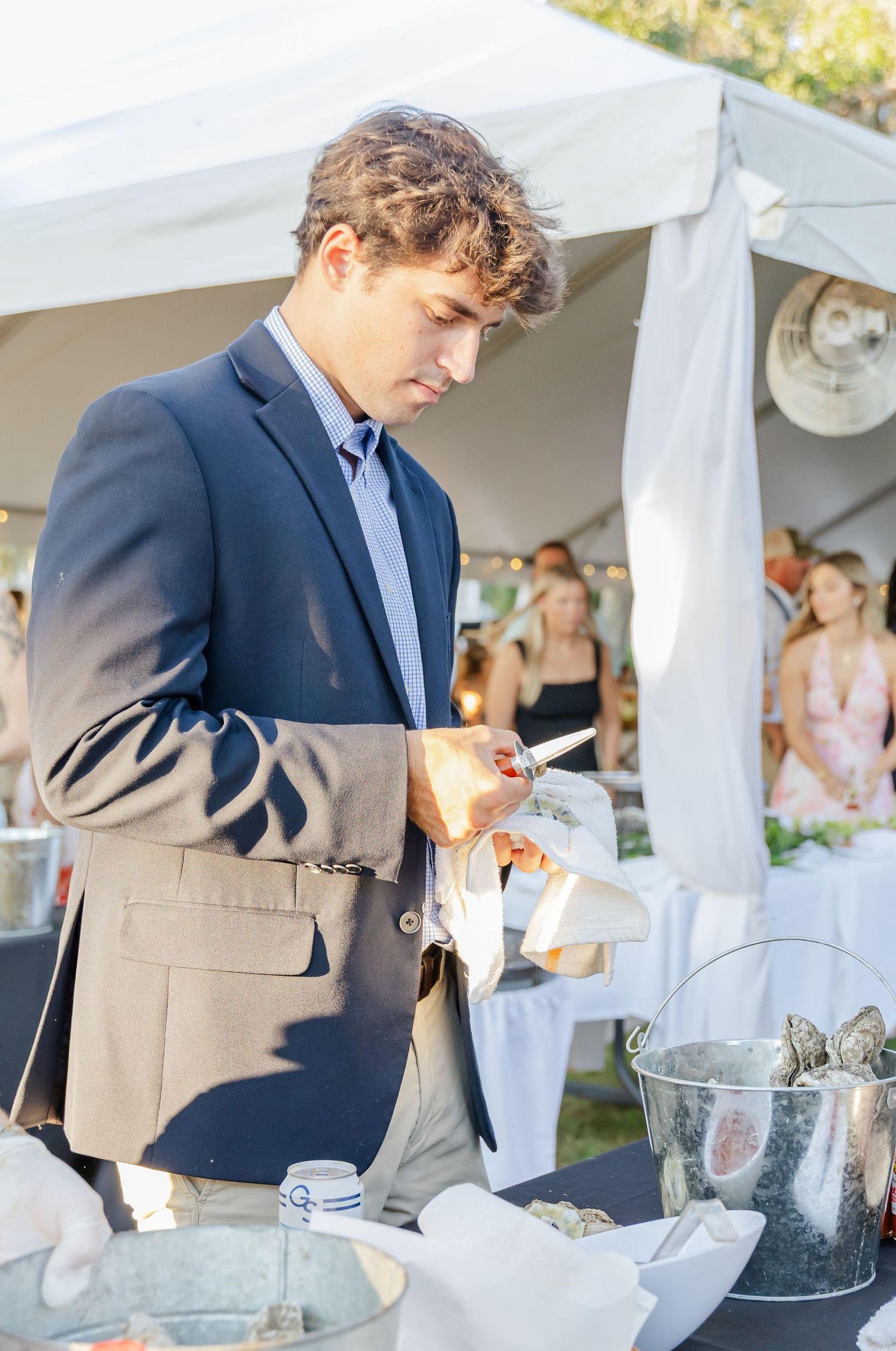 Wedding guests enjoy refreshments under an elegant white tent during an outdoor reception celebration.
