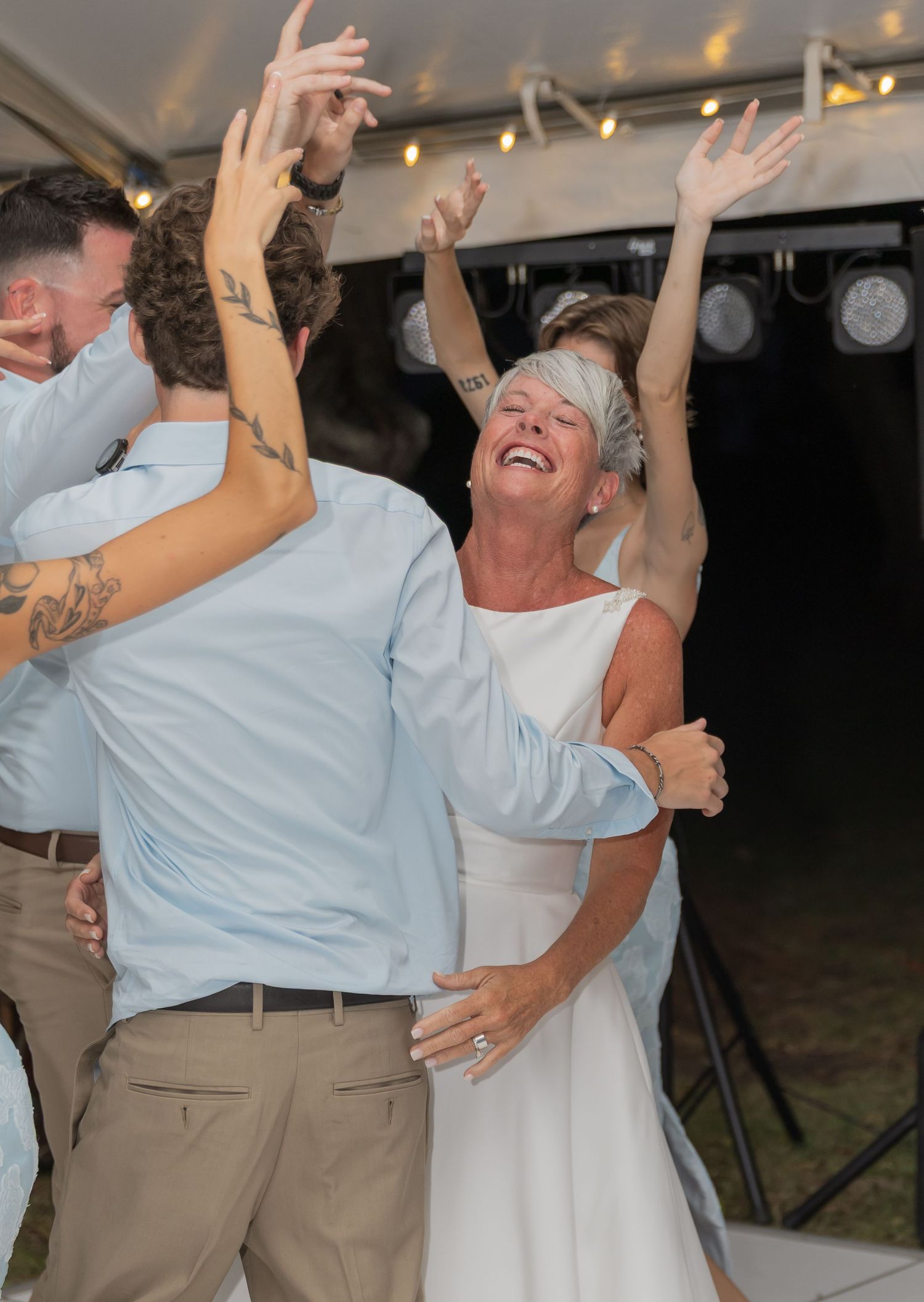 Energetic dancing and celebration at a nighttime outdoor wedding reception.