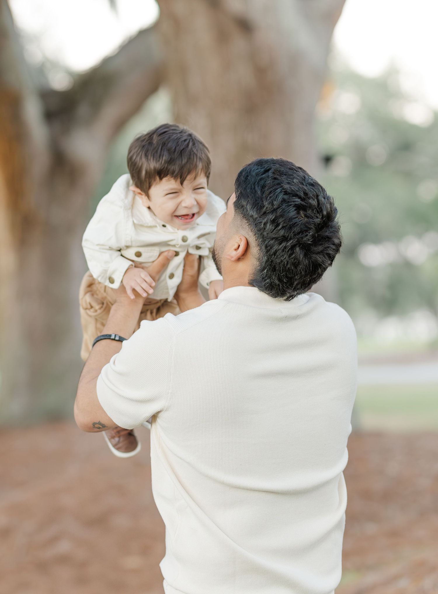 Sweet candid moments shared between family members in a park with fallen leaves.