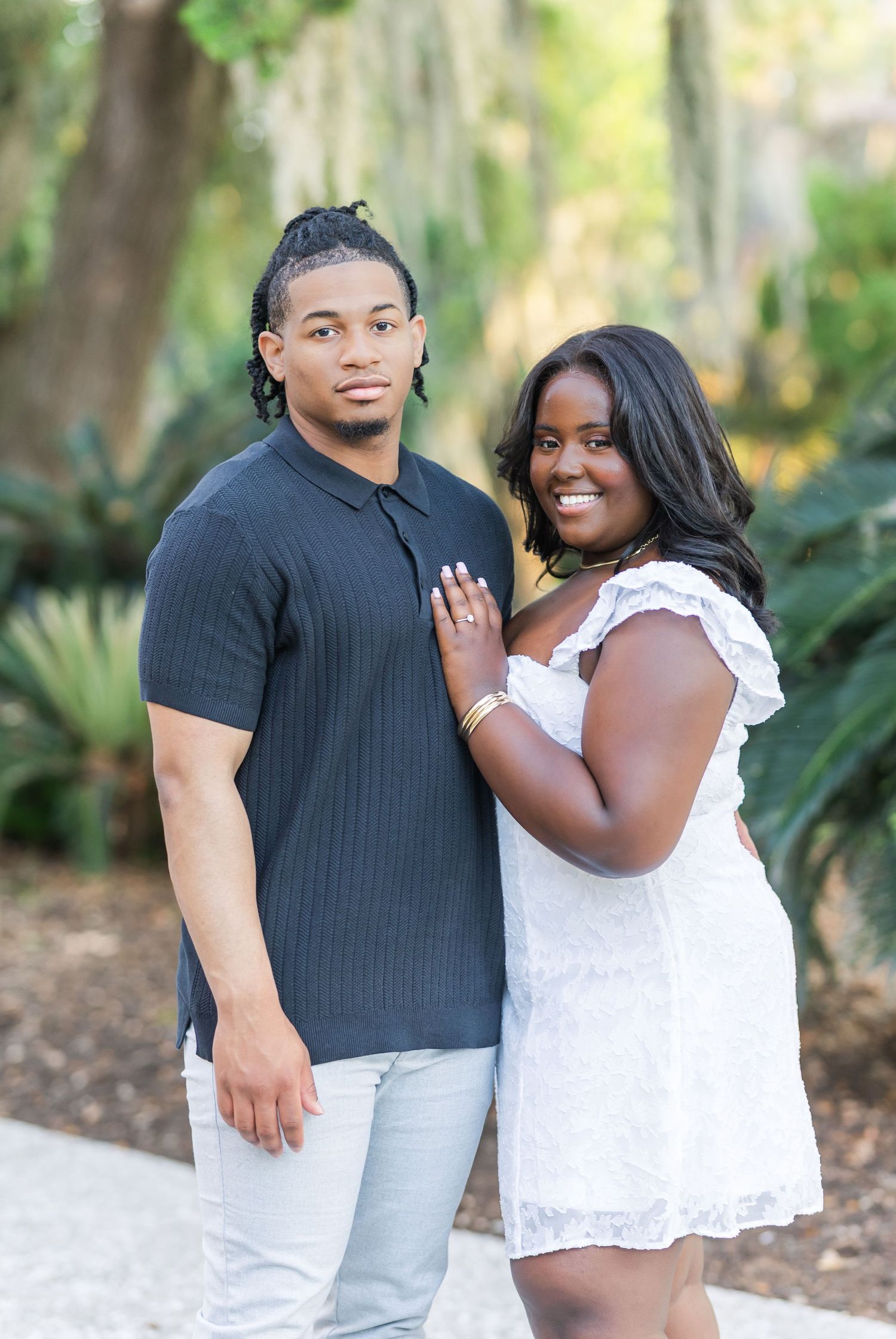 Couple poses together against a lush garden backdrop during their engagement session.