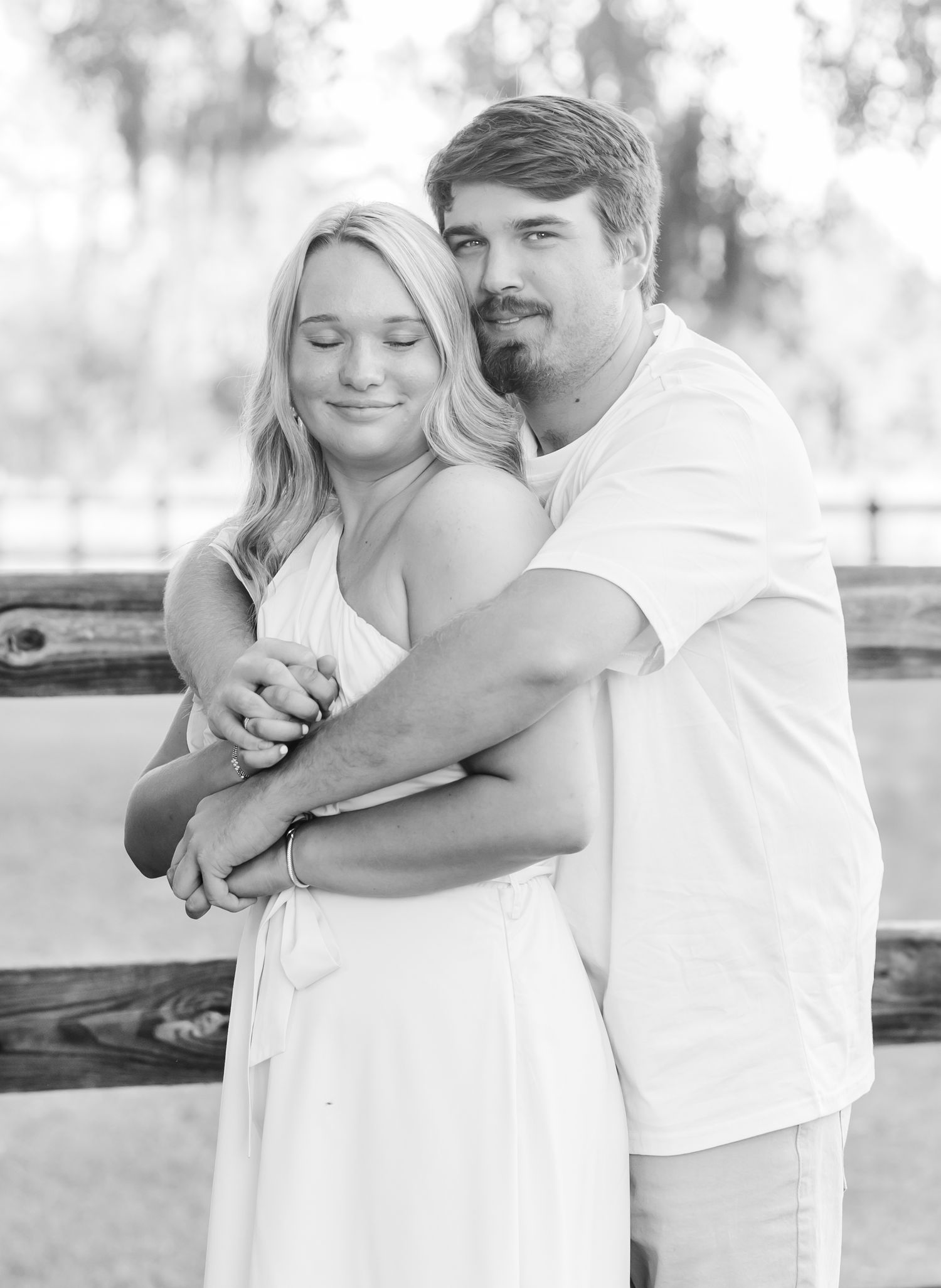 A series of black and white photos showing tender moments between a couple embracing outdoors in casual white attire.