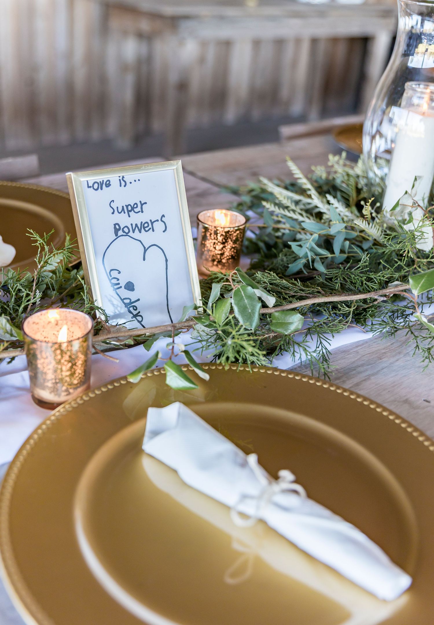 Wedding table detail with gold plate, handwritten card, and mercury glass votives.