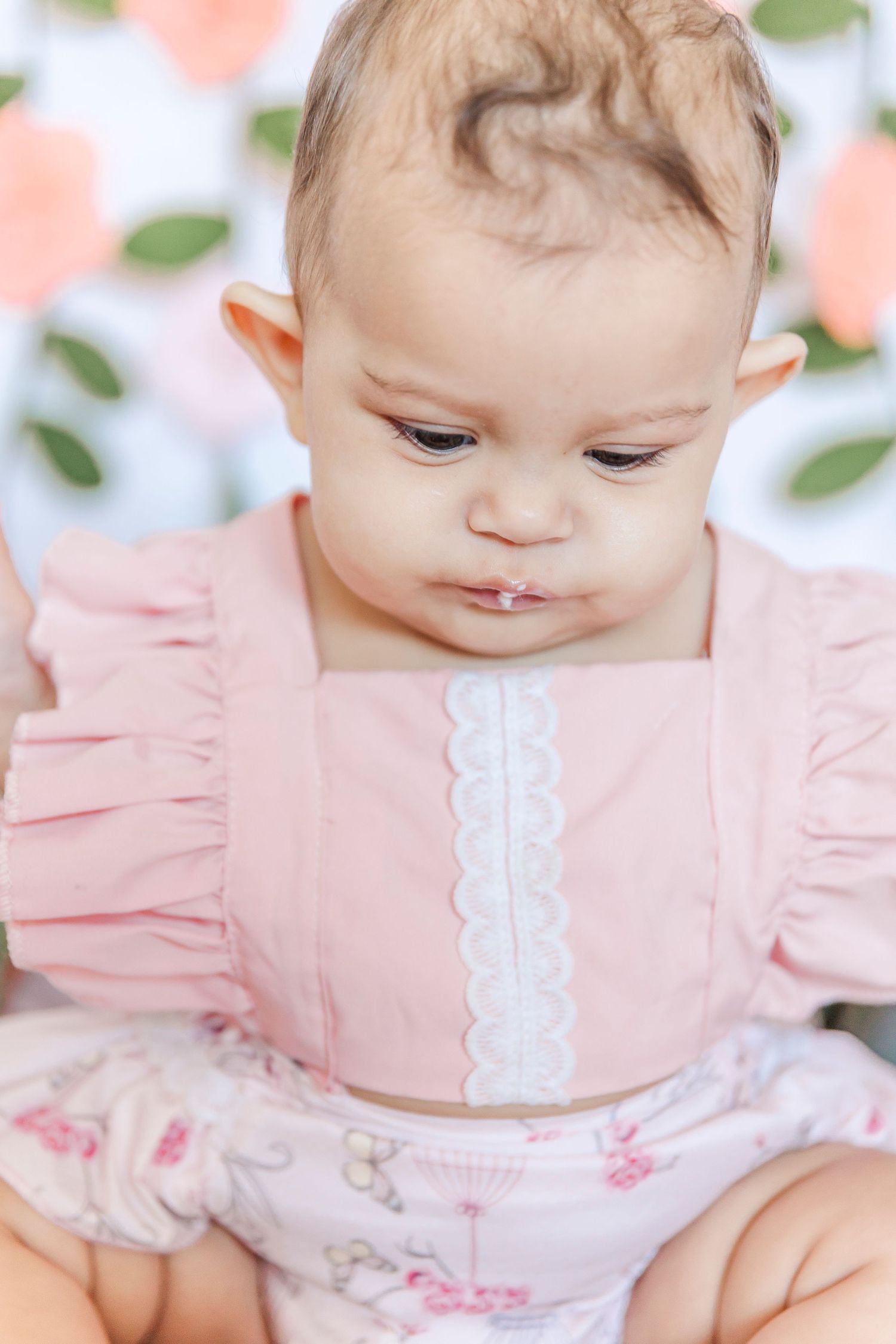 Close-up of baby wearing pink ruffled dress with white lace trim.
