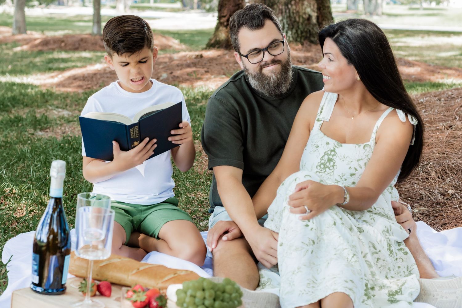 Family sharing quality time while reading during outdoor picnic.