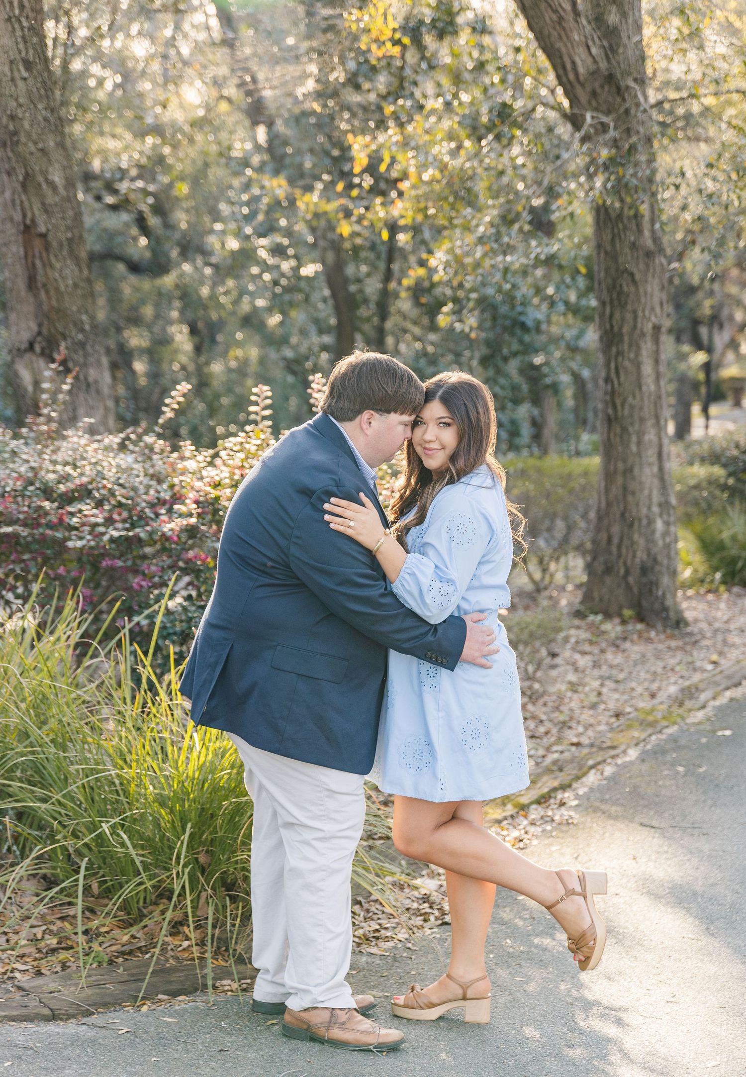 A happy couple embraces on a garden path surrounded by blooming spring foliage.