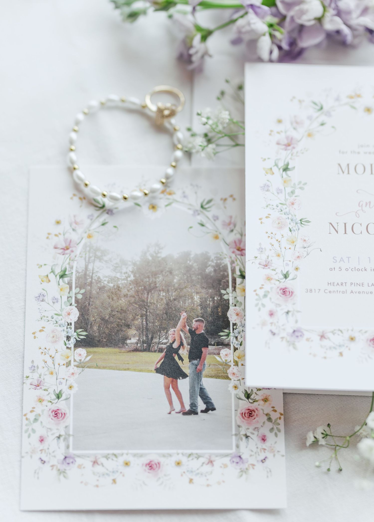 Wedding stationery with engagement photo and pearl accessories styled with delicate flowers.
