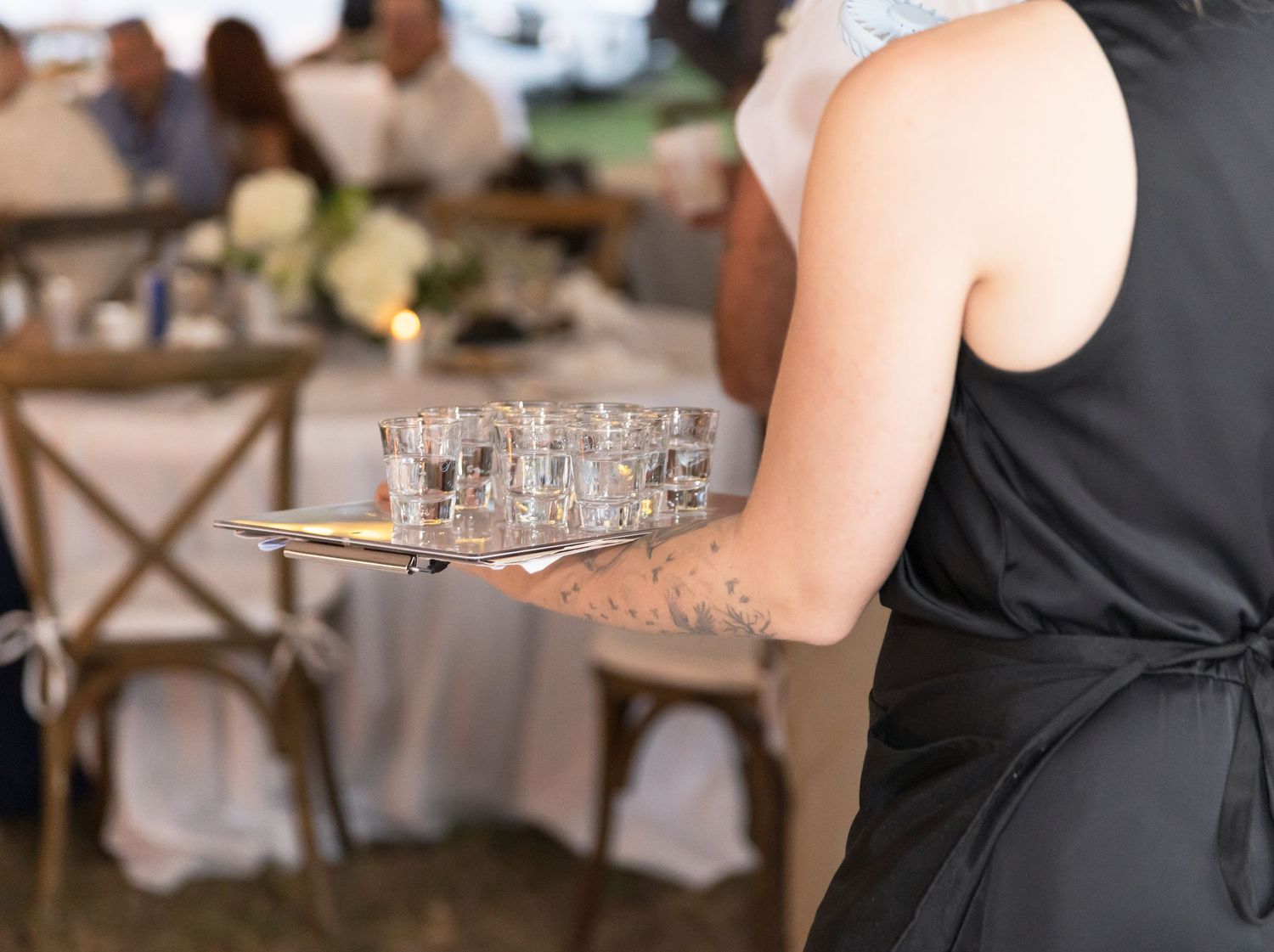 Event staff in black attire carrying trays of drinks at a formal reception.