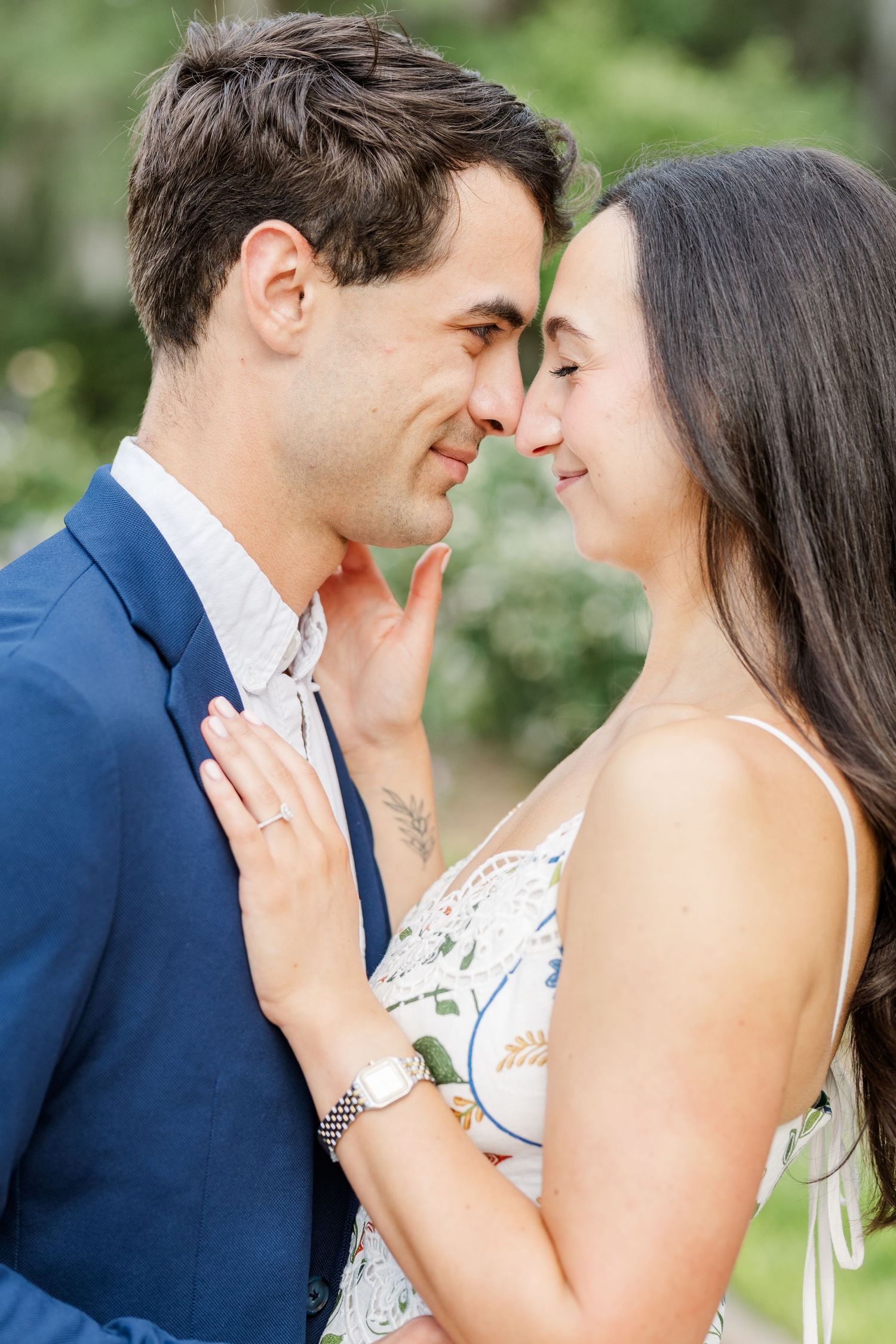 Close-up of an engaged couple leaning in for a gentle nose-to-nose moment outdoors in soft natural light.