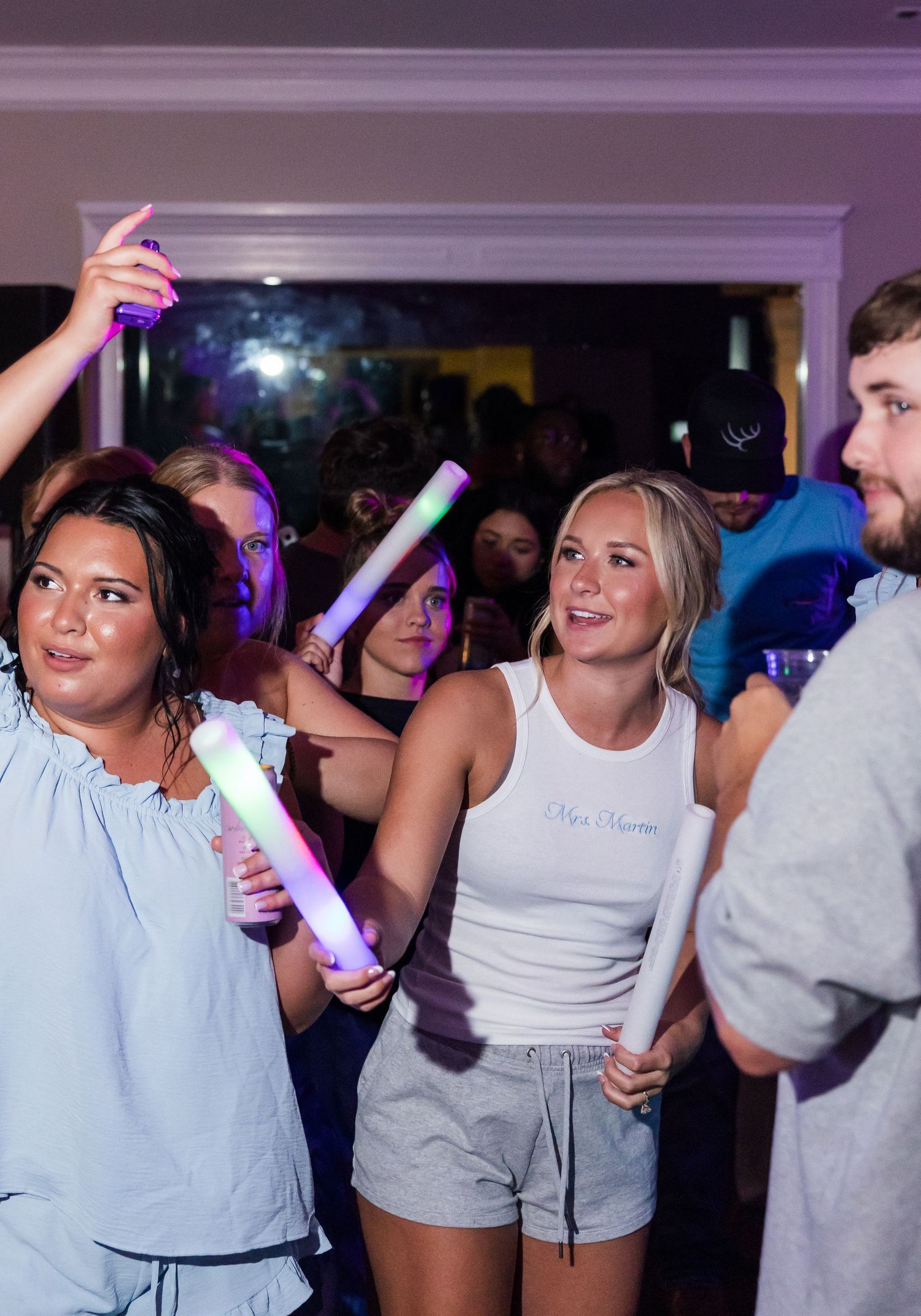Wedding guests dance and celebrate with glowing foam sticks at a lively reception party.