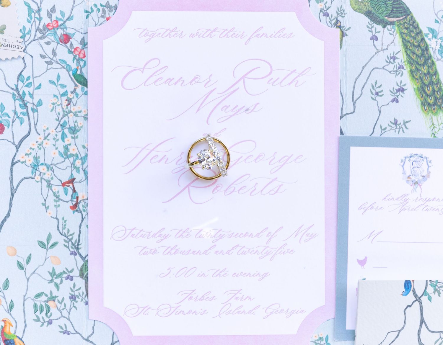 A wedding invitation with floral wallpaper background and a delicate gold wax seal on pink stationery.