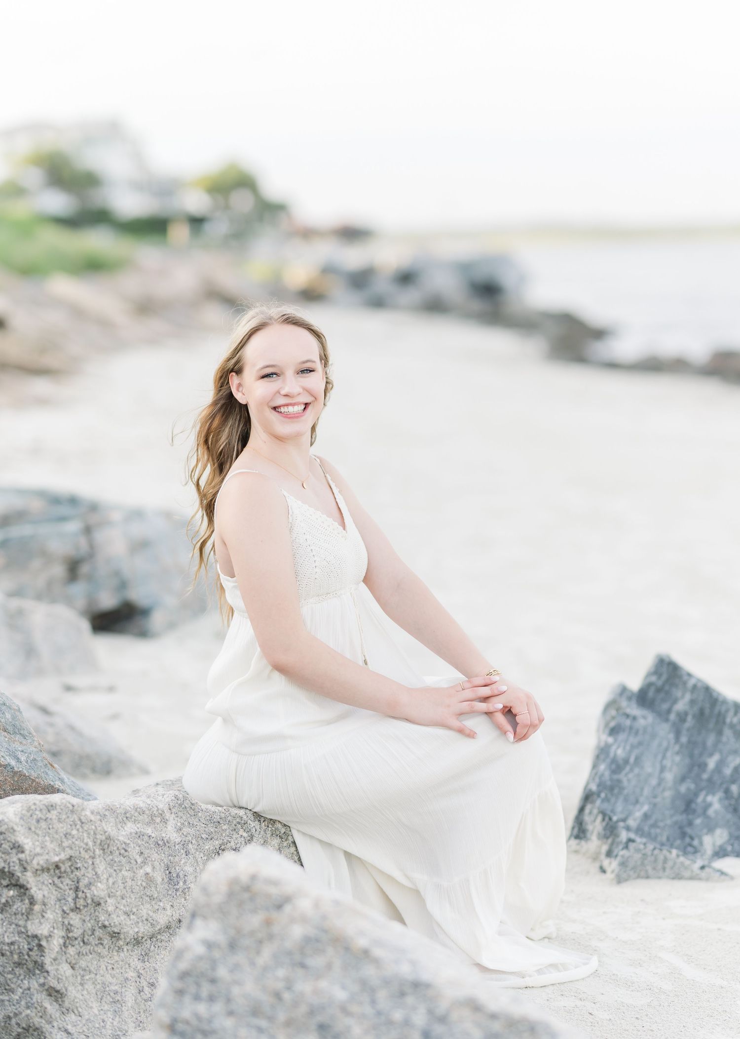Serene coastal portrait on rocky beach with gentle waves in background.