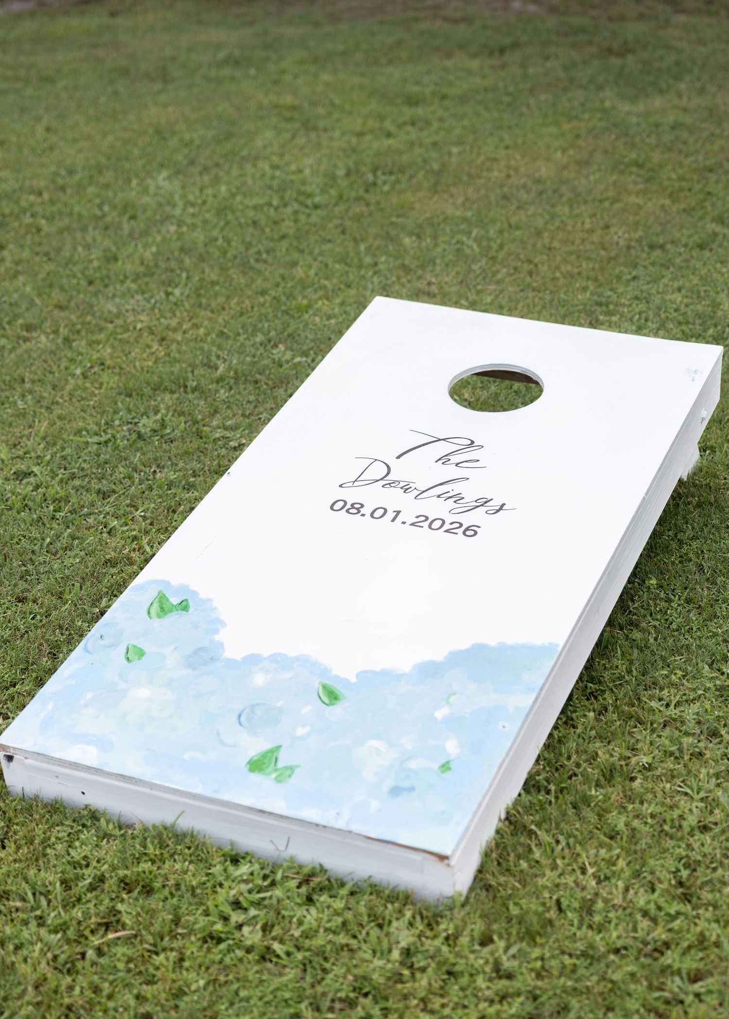 Custom cornhole board with floral design reading The Darlings 08.01.2026, perfect for wedding lawn games.