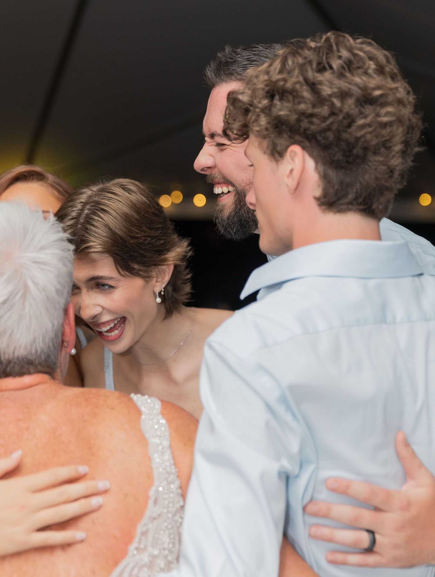 Guests dancing and celebrating at a joyful wedding reception under a tent.