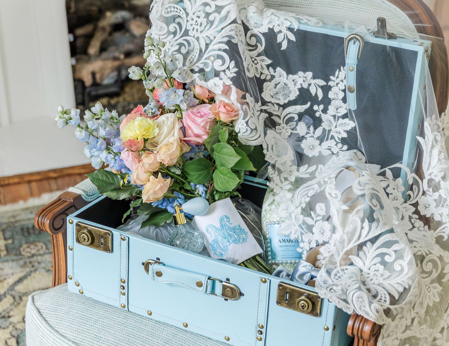 Vintage blue suitcase decorated with lace and filled with romantic pastel floral arrangements.