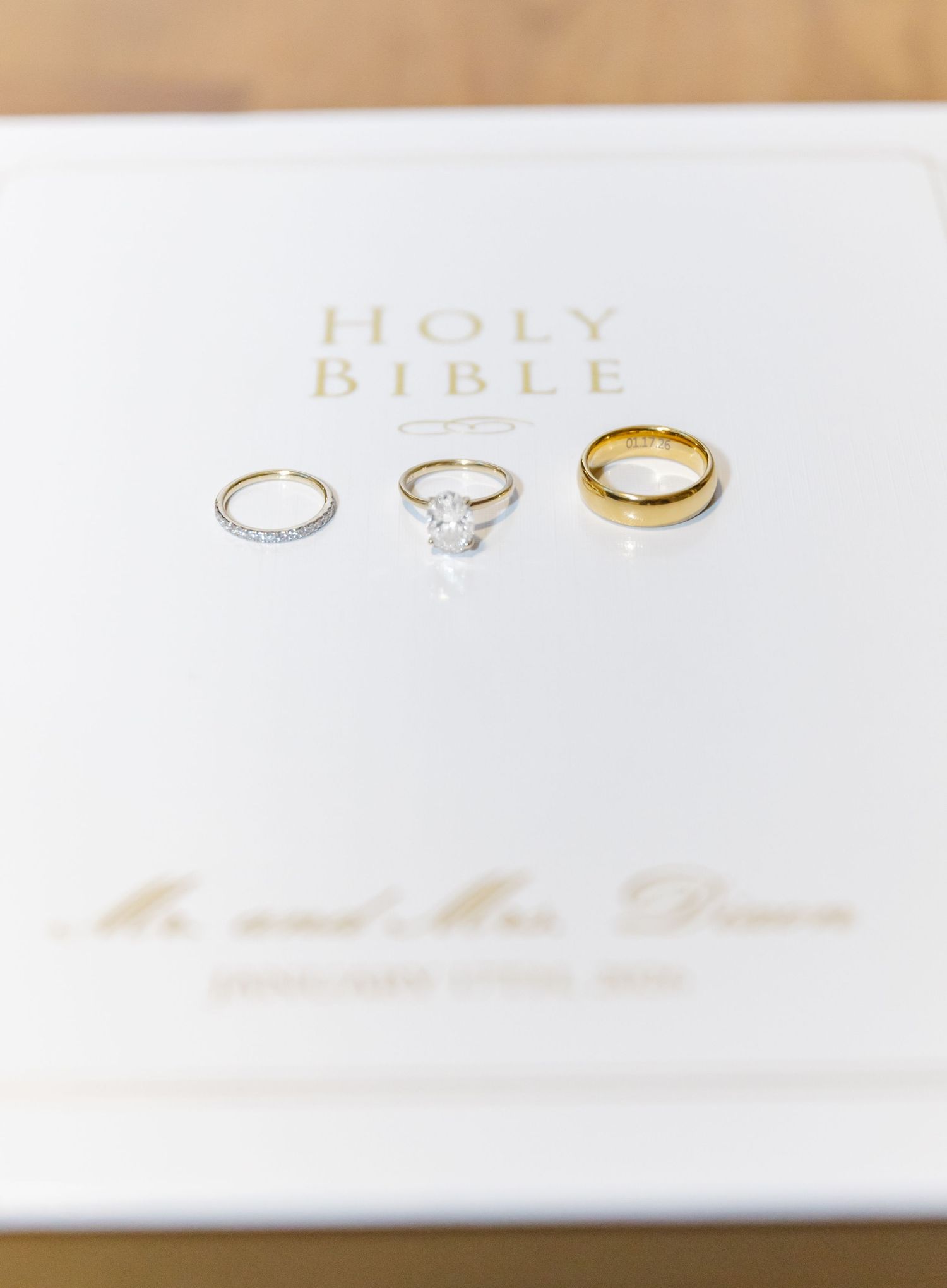 Wedding rings and a Holy Bible arranged on a white surface in elegant minimalist styling.