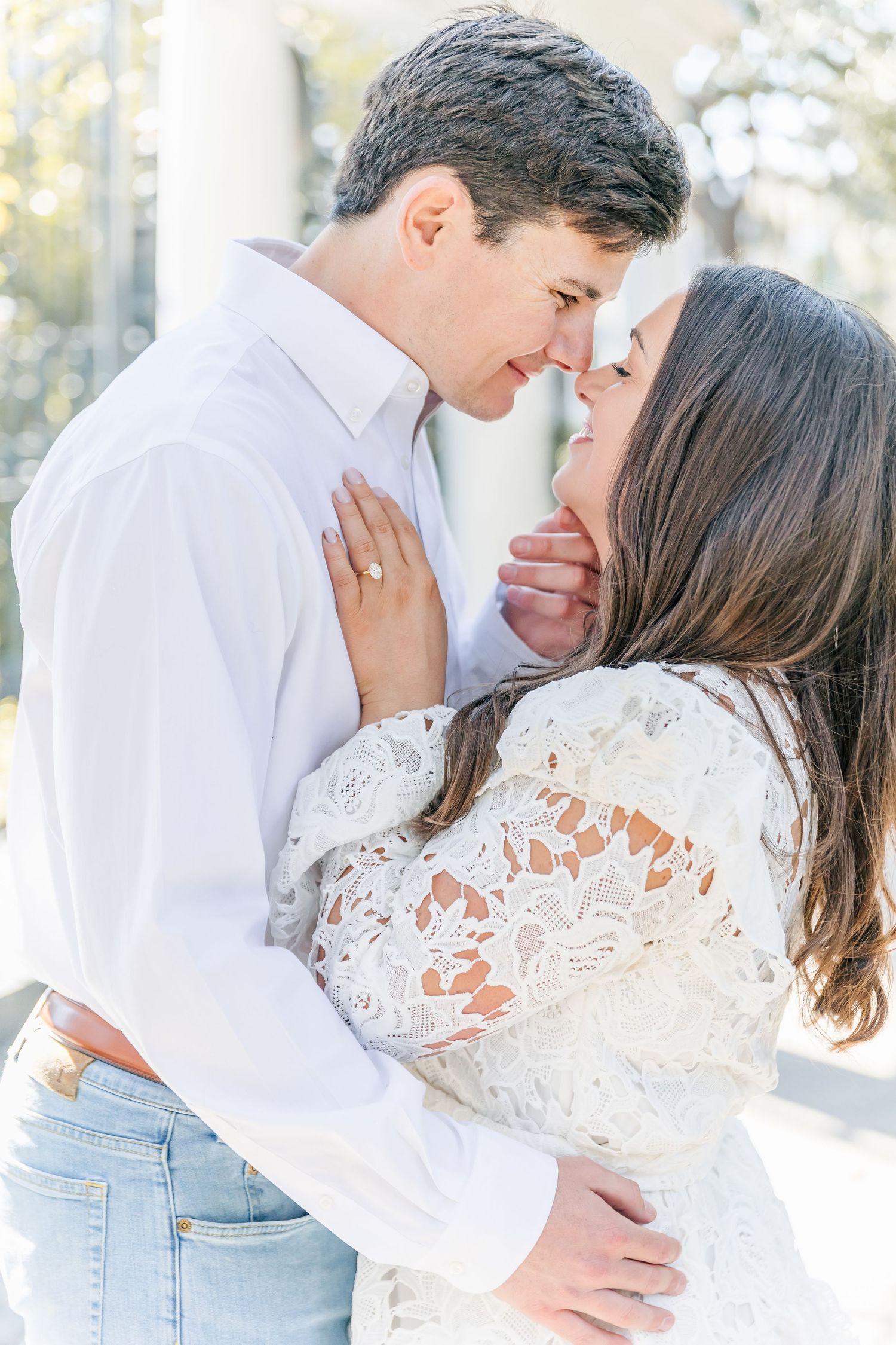 Intimate moment captured between couple in white lace dress and crisp button-down shirt.