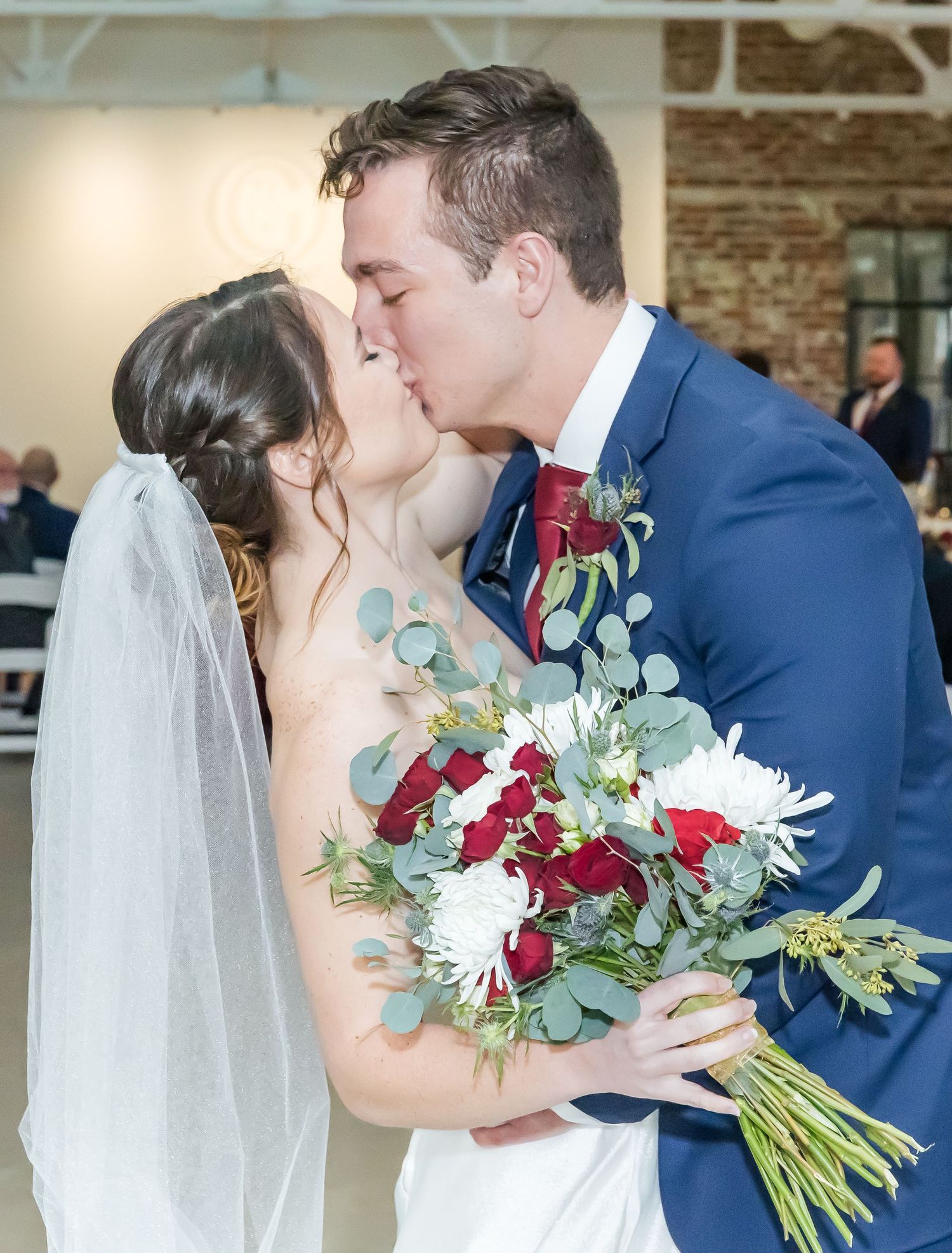 Romantic wedding moments with red and white bouquets against a brick wall backdrop.
