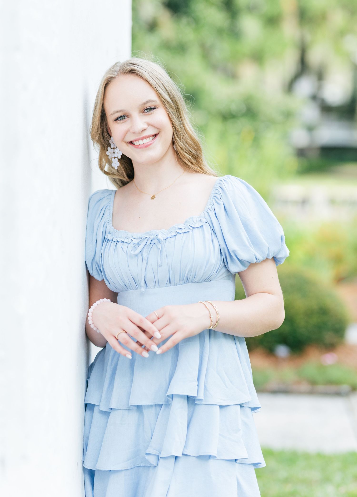 Light blue tiered ruffle dress photographed outdoors in a garden setting with soft natural lighting.