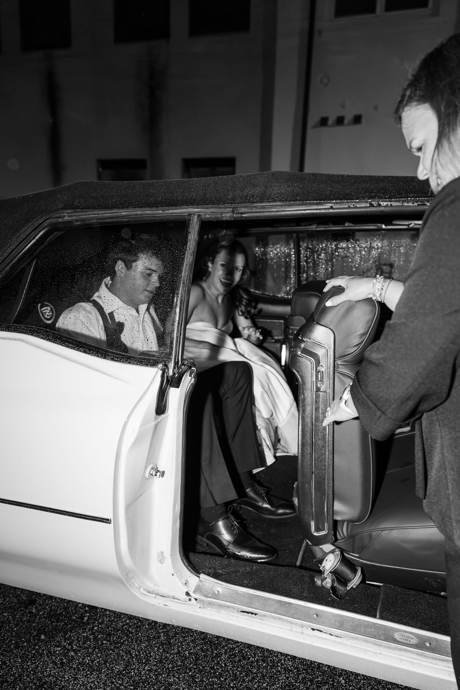 Bride and groom getting into a classic white car after their wedding reception.