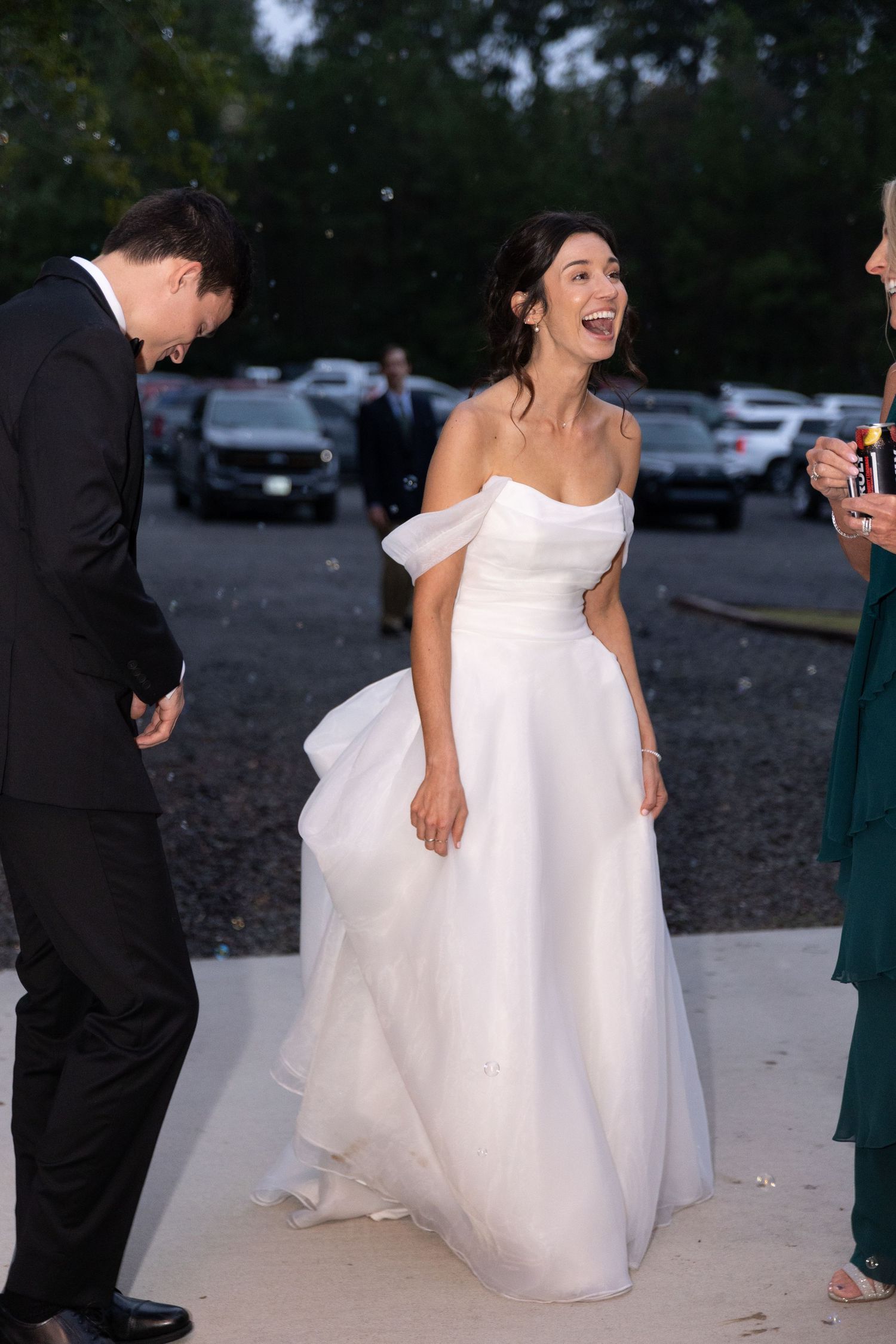 Bride in flowing white gown twirls joyfully during outdoor wedding celebrations.