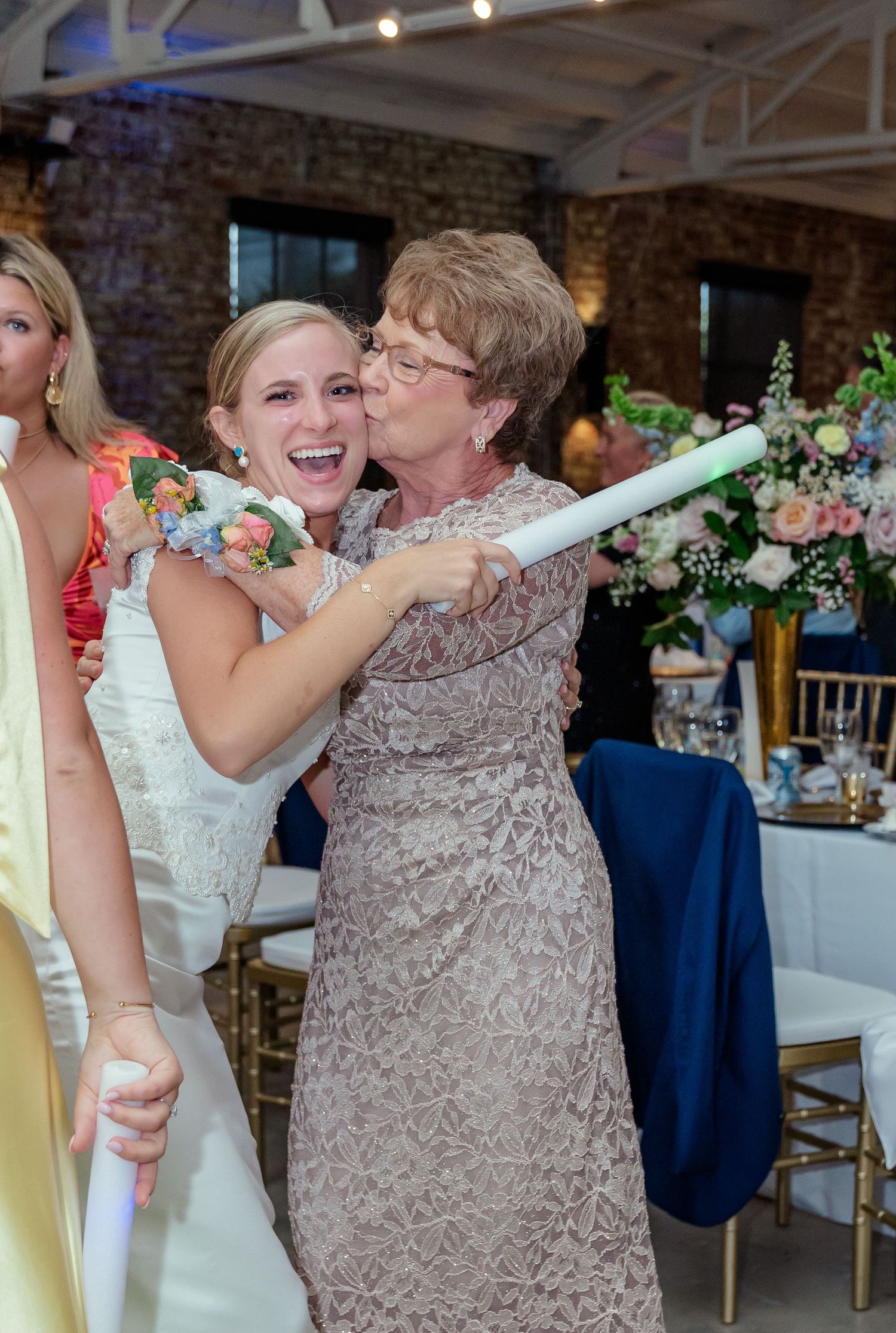 Wedding guests share joyful moments while playing a party game with glowsticks at an indoor reception venue.
