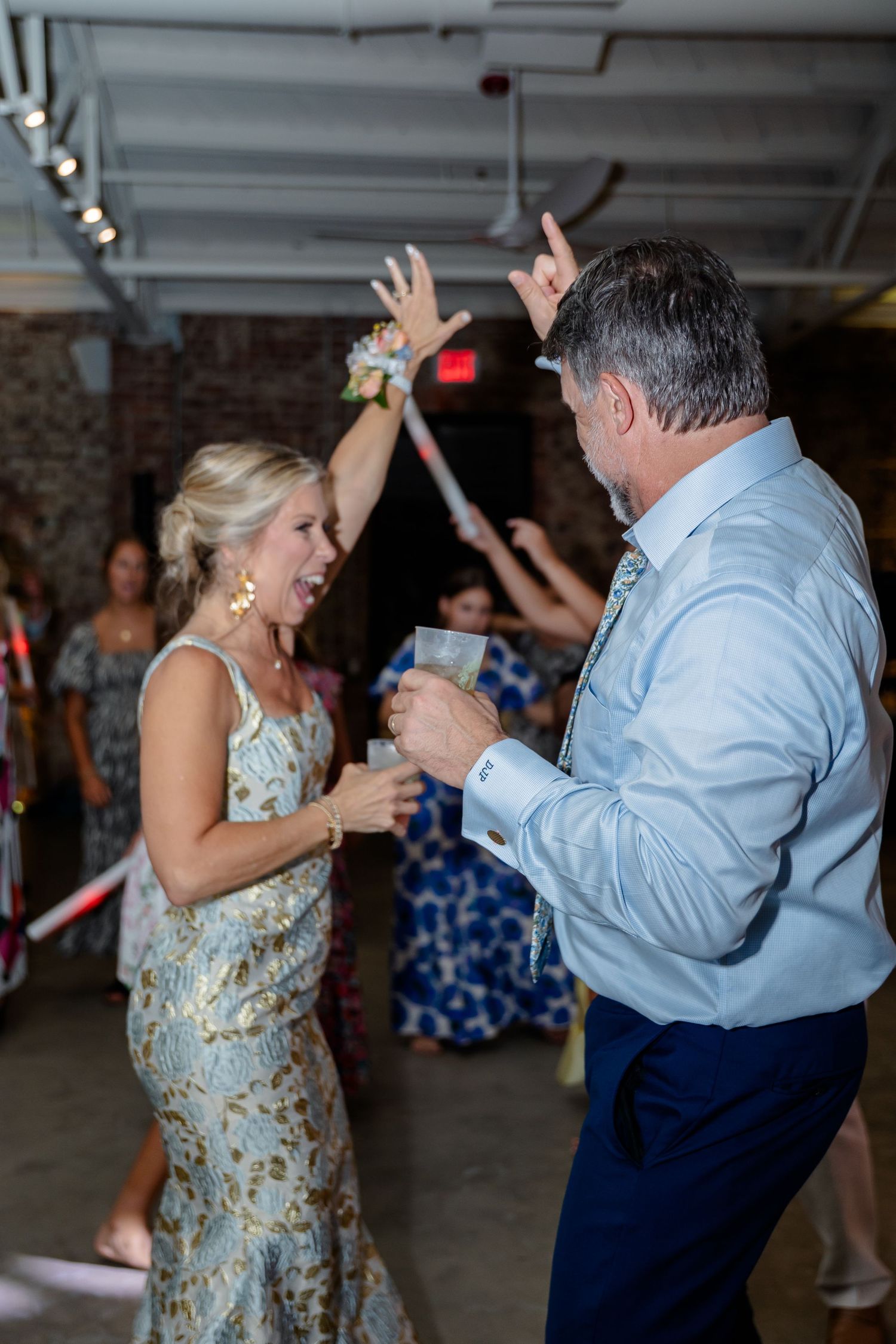 Wedding guests dancing with light-up foam sticks in a converted warehouse venue.