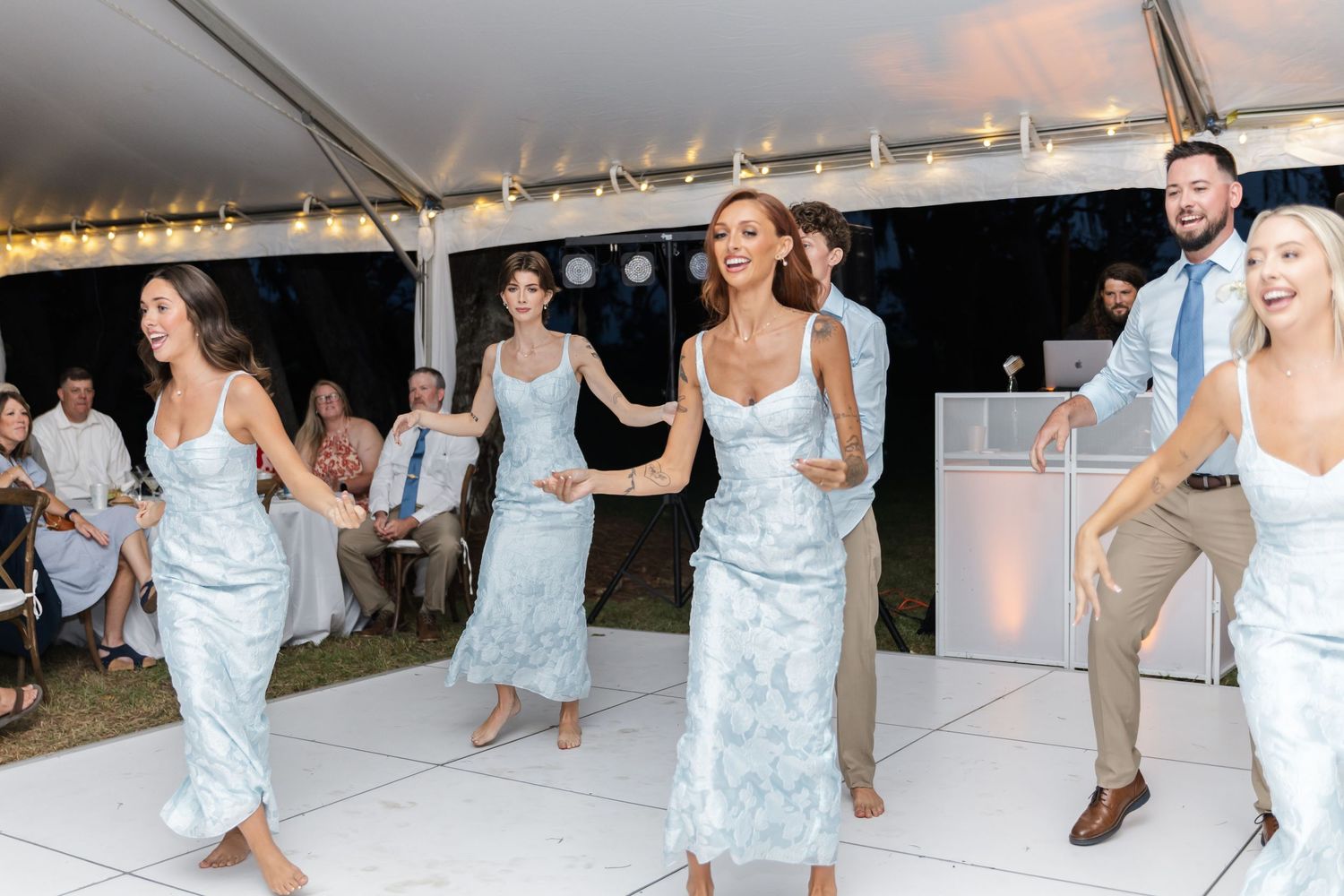 Wedding celebration features coordinated dance moves by bridesmaids in matching blue dresses.