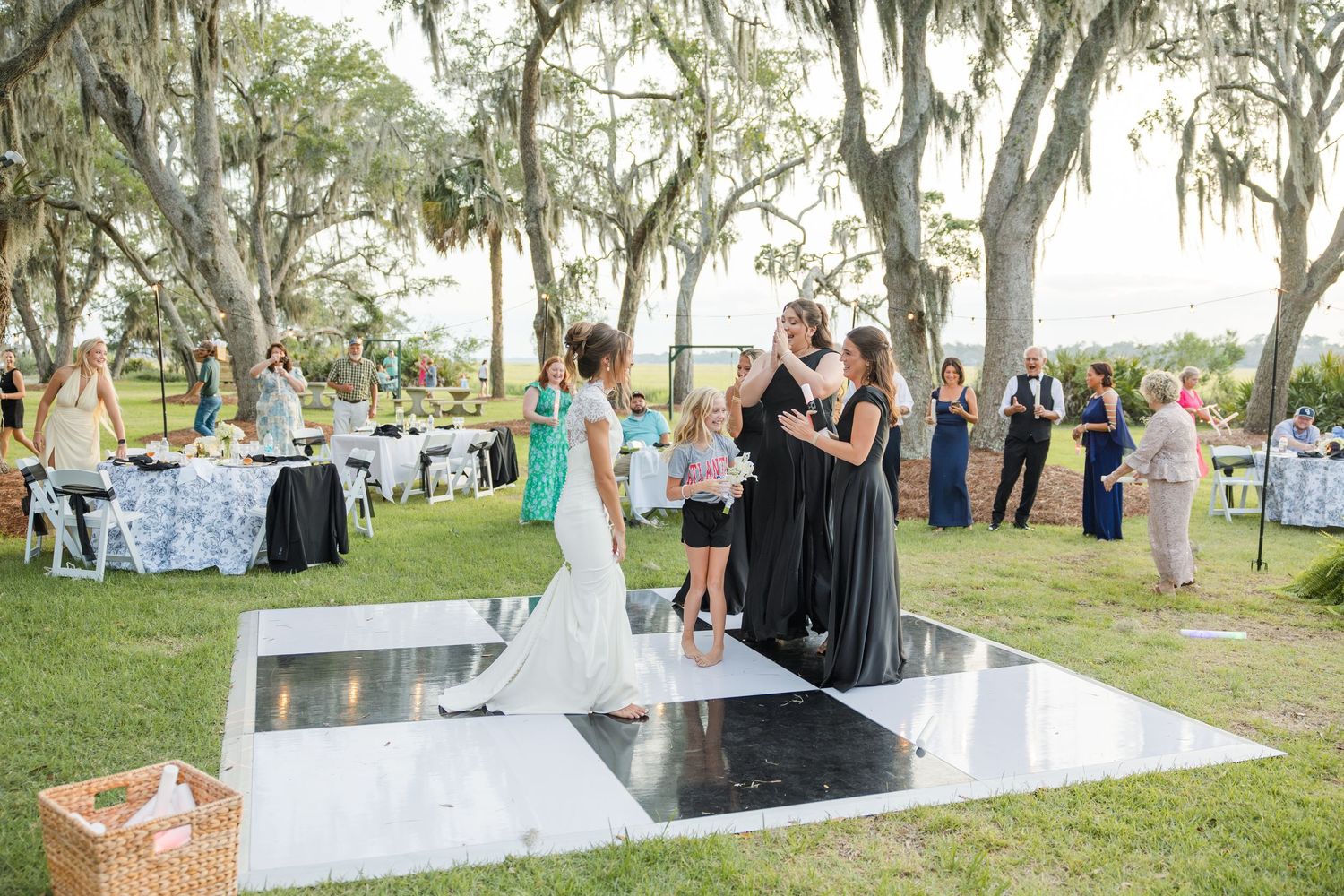 Outdoor wedding reception on a dance floor under Spanish moss-draped trees with guests in formal attire.