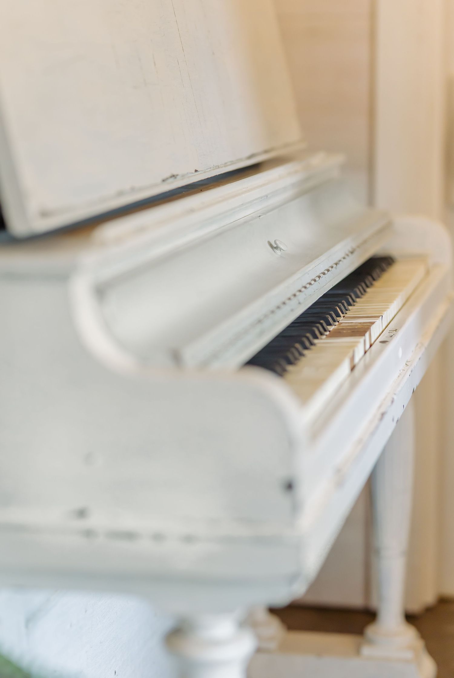 White upright piano photographed from different angles showing elegant curves and glossy finish in soft natural light.