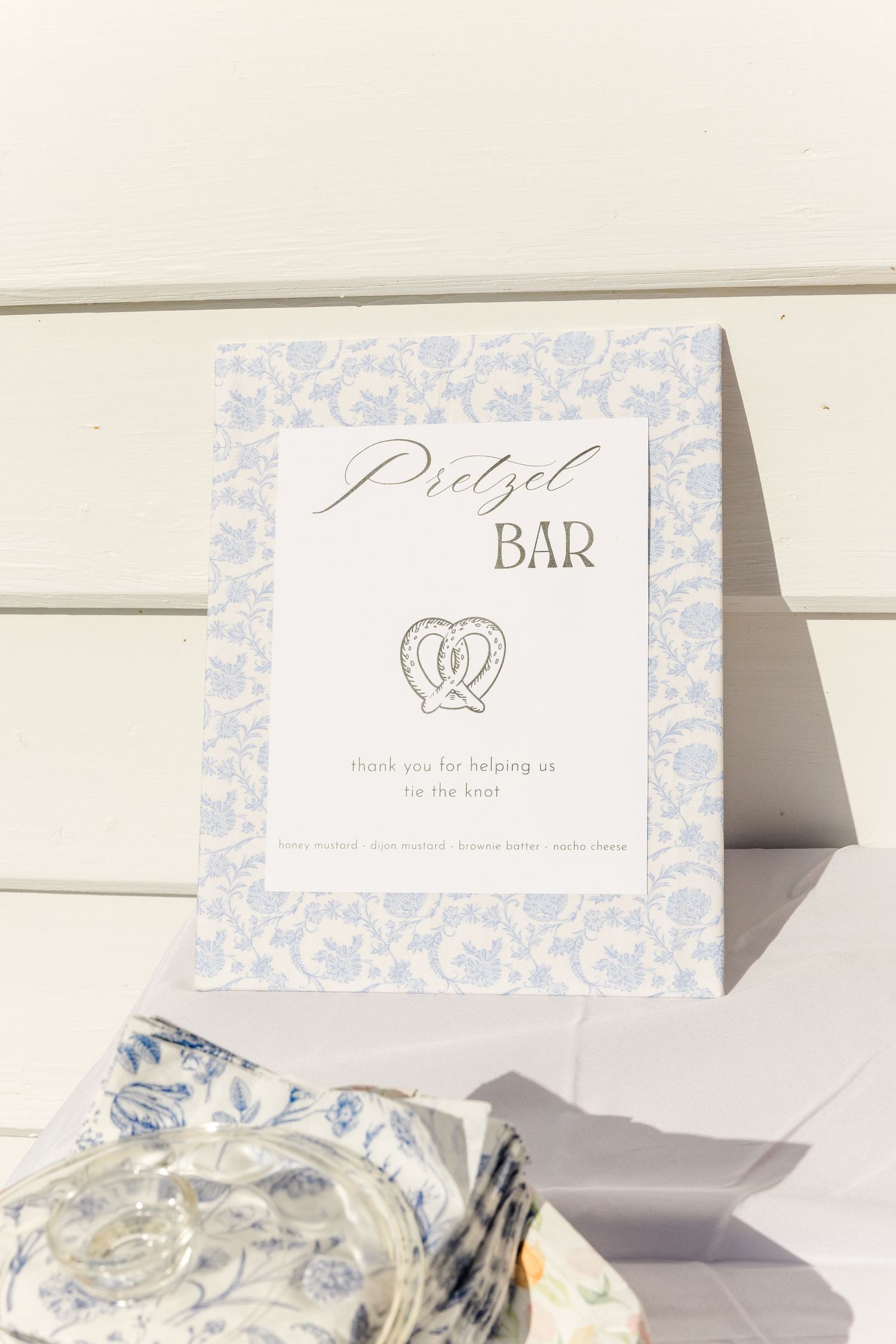 Elegant pretzel bar sign with blue floral border for a wedding reception.