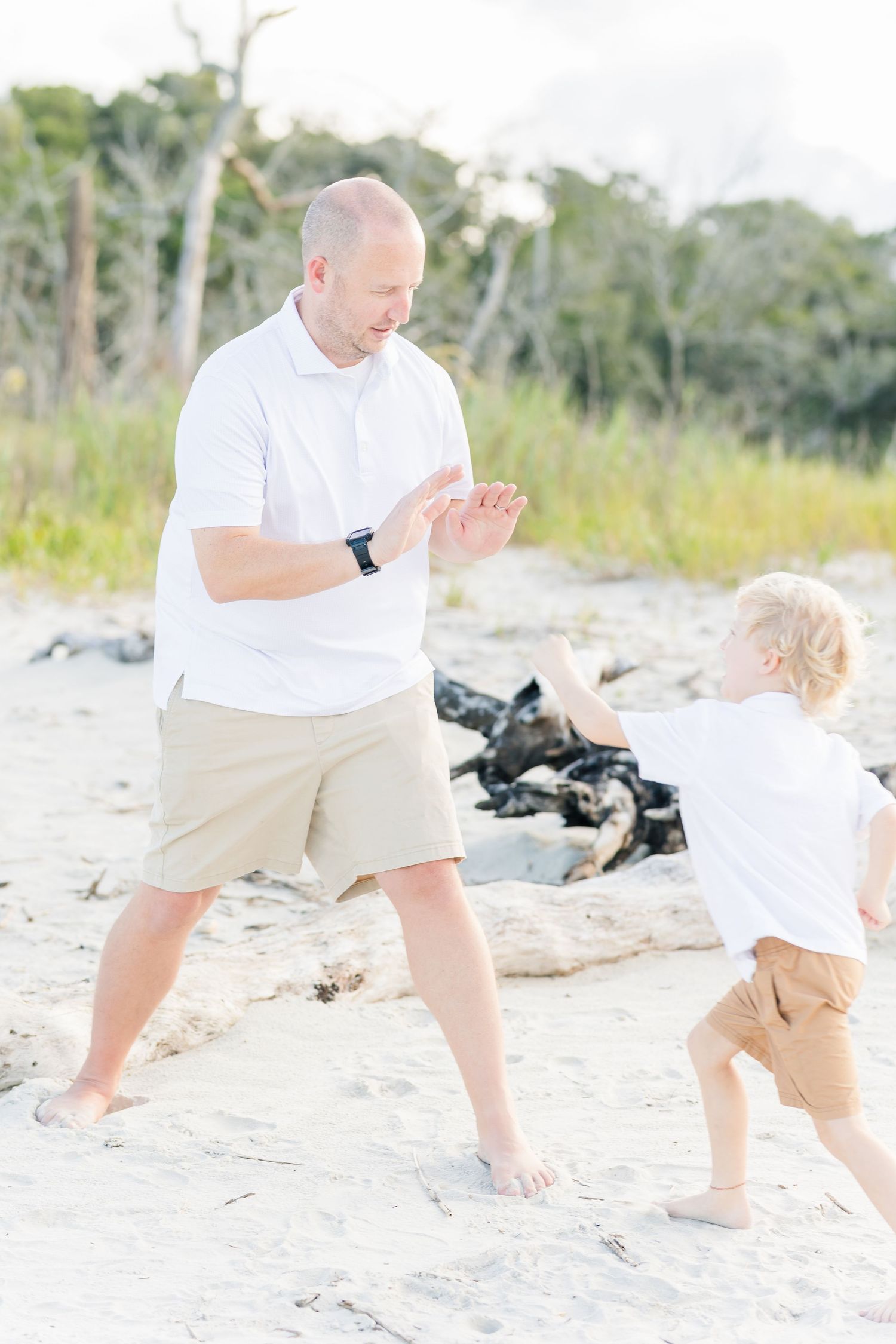 Playful moment between parent and child dancing on sandy beach.