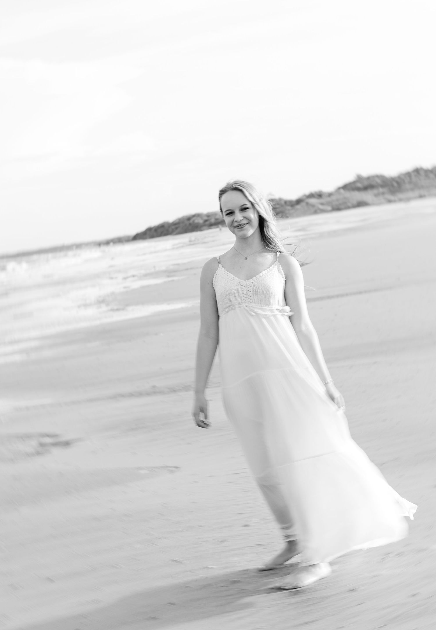 Black and white photo of flowing white dress on a peaceful beach setting.