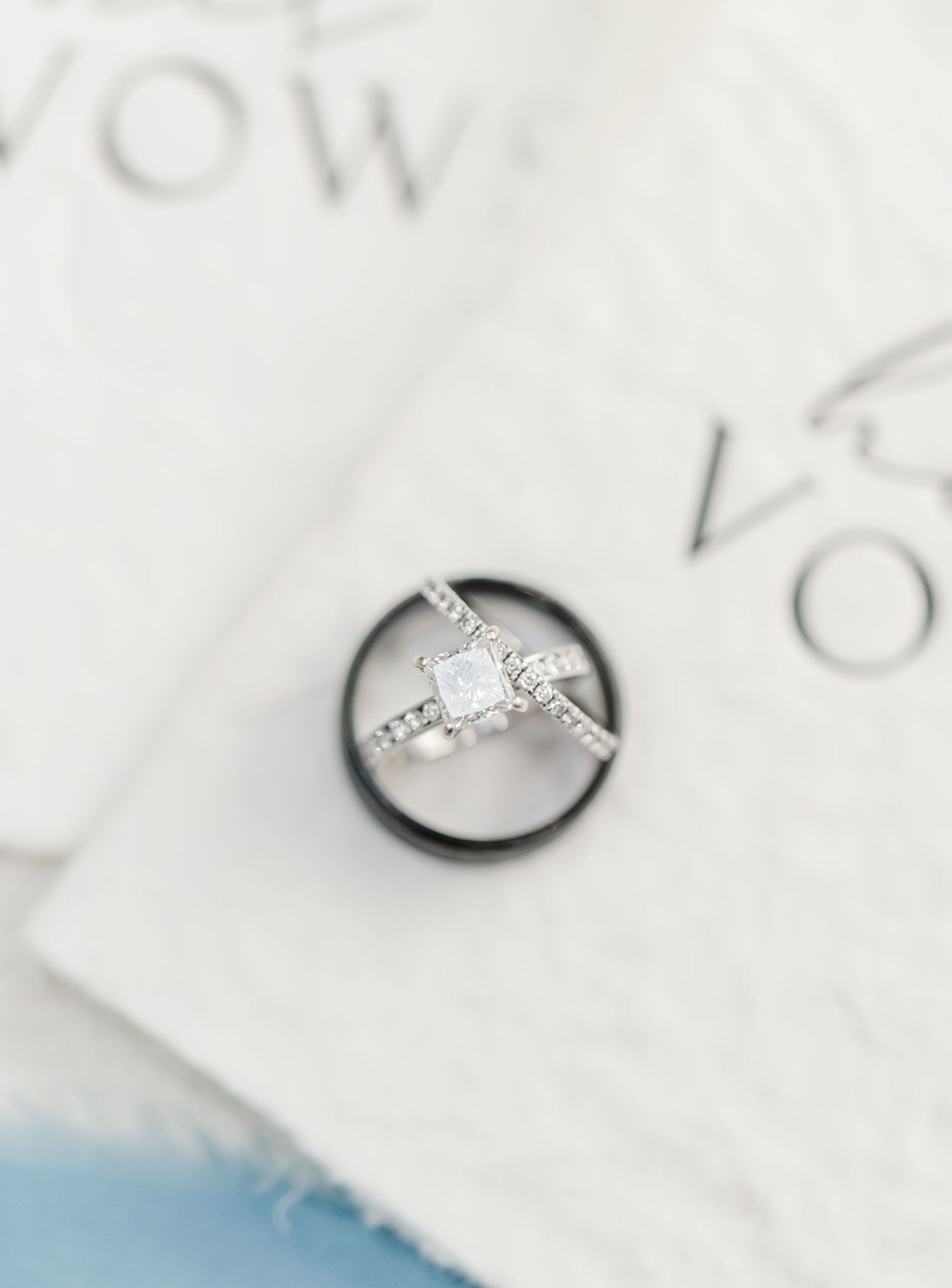 Close-up view of a delicate diamond engagement ring with a solitaire stone on a white textured background.