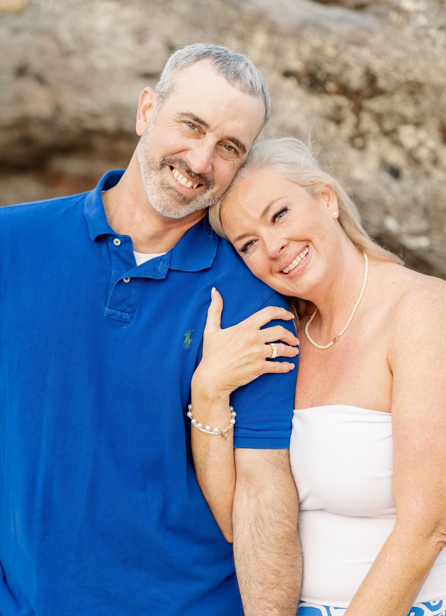 A romantic portrait of a mature couple embracing outdoors in coordinated blue and white outfits.