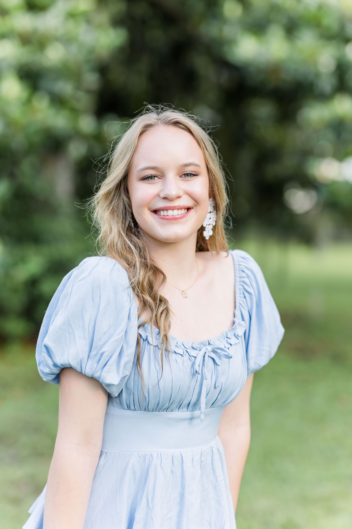 A light blue dress with puff sleeves is showcased in a garden setting during a bright summer photoshoot.