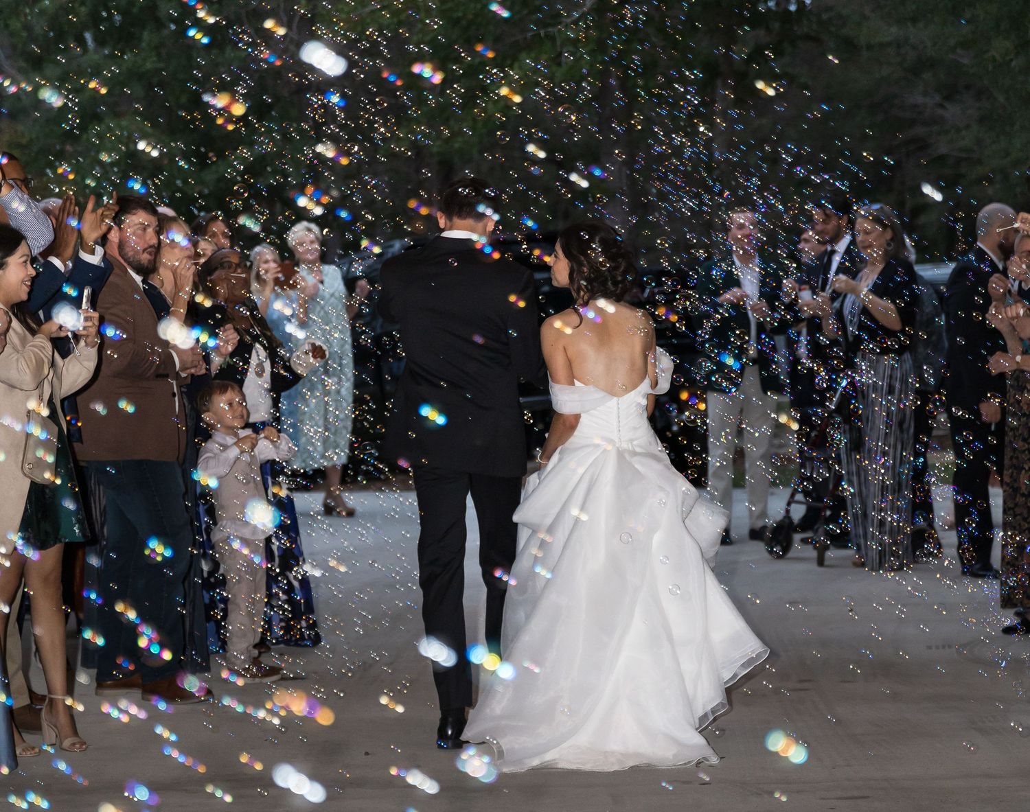 Wedding celebration with confetti being thrown at night as guests celebrate outside.