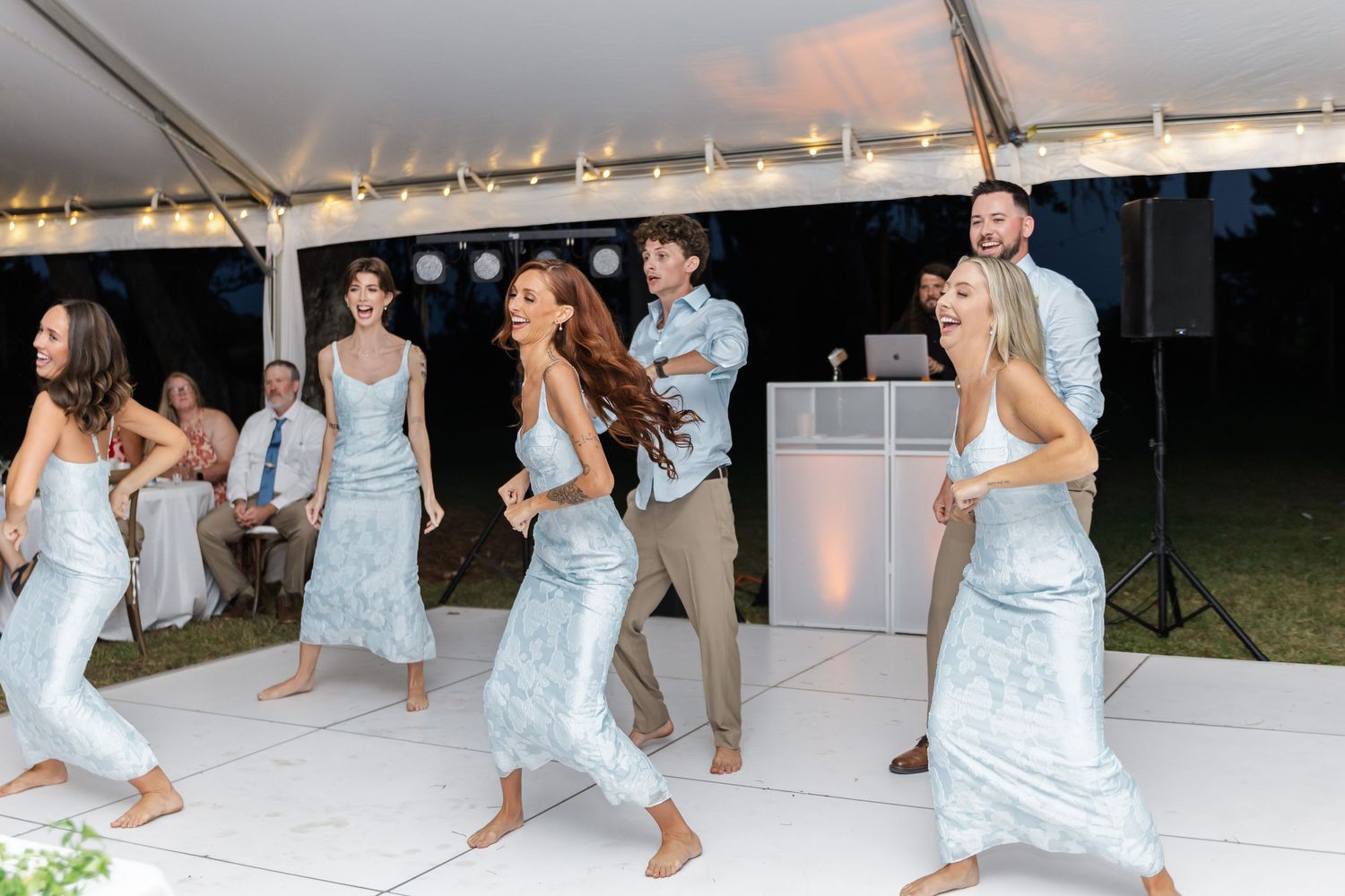 Bridesmaids in pale blue dresses perform a choreographed dance routine at a wedding reception.