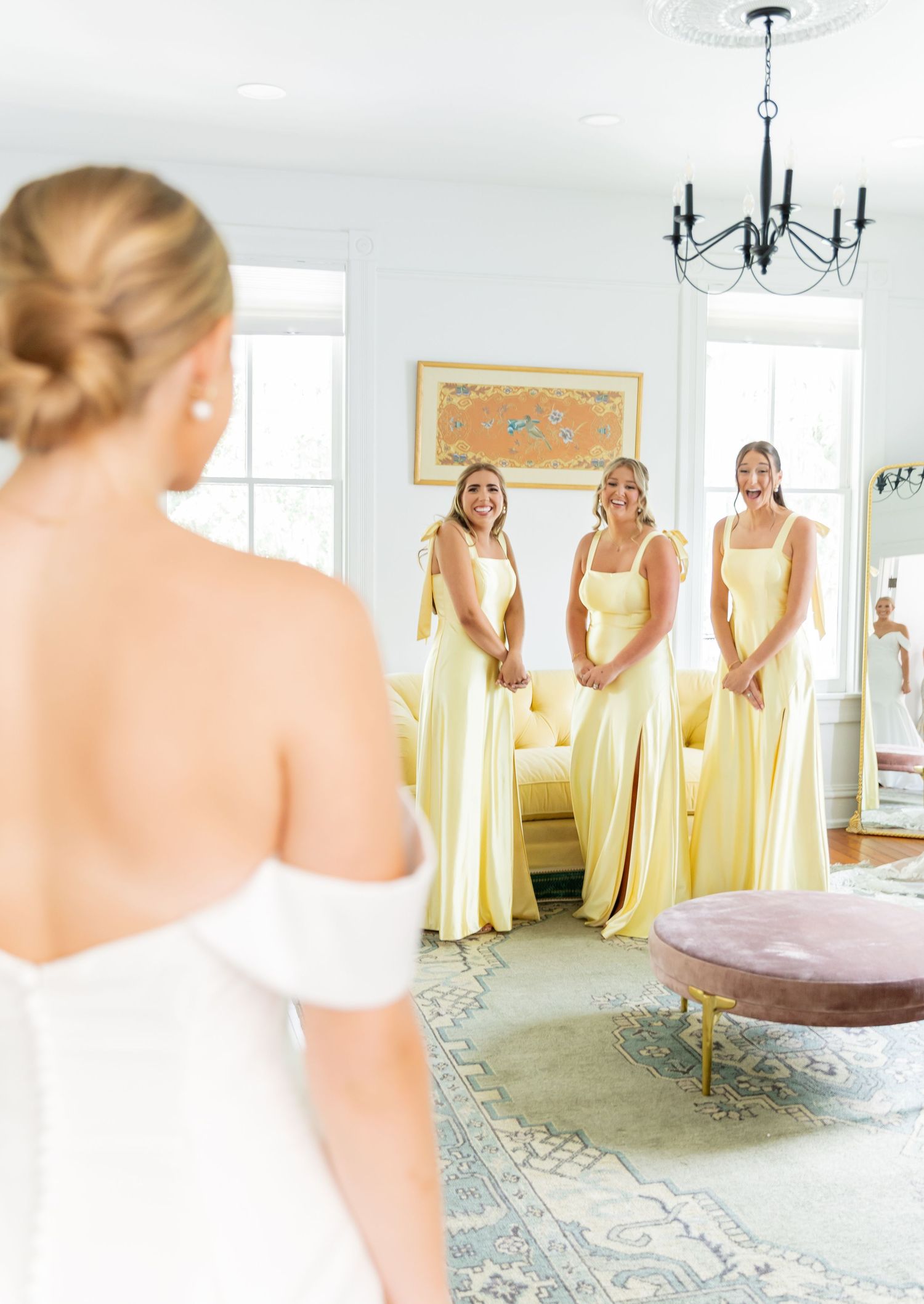 Bridesmaids in pale yellow dresses gather in a sunlit room with elegant decor.