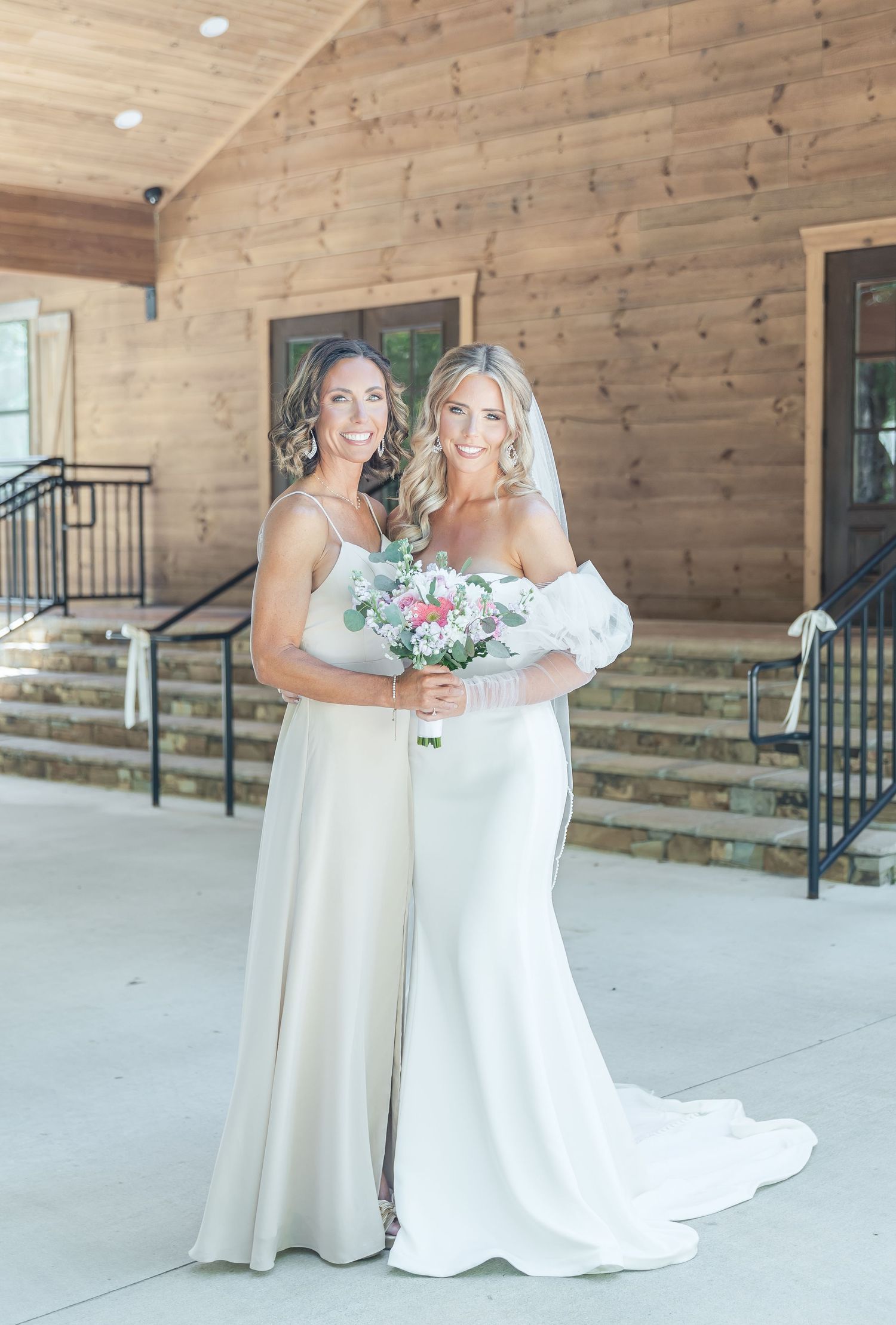 Elegant bridal portrait with soft lighting and pink floral bouquet at rustic venue.
