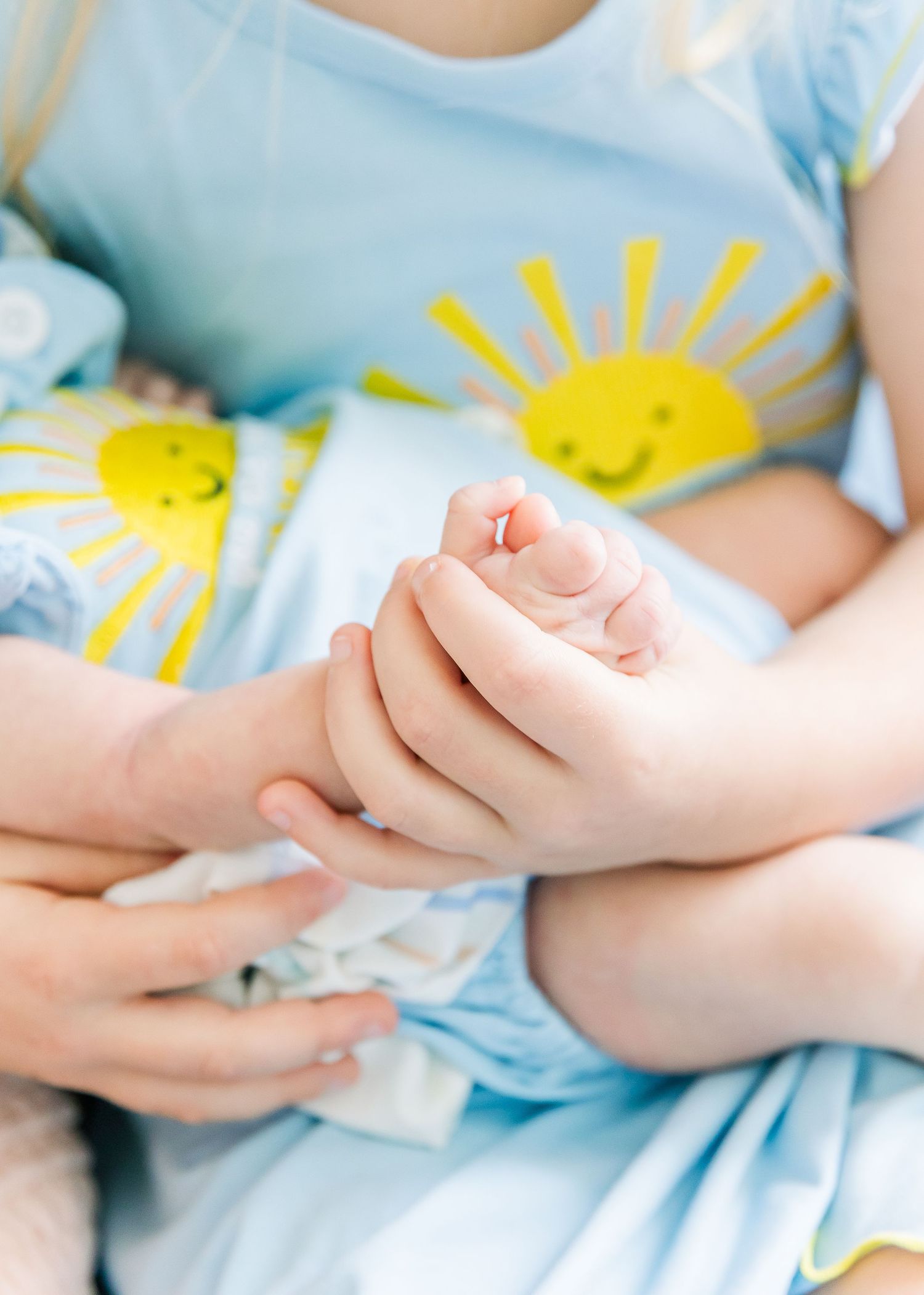 Close up of hands resting on blue dress with sunny yellow pattern.