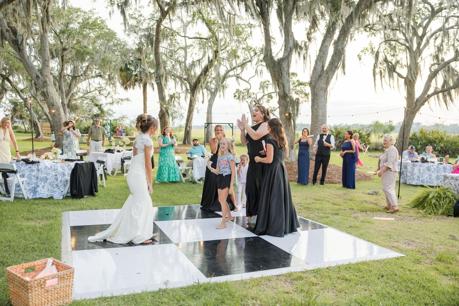 Wedding guests celebrate on outdoor dance floor surrounded by Spanish moss trees at a scenic Southern plantation venue.