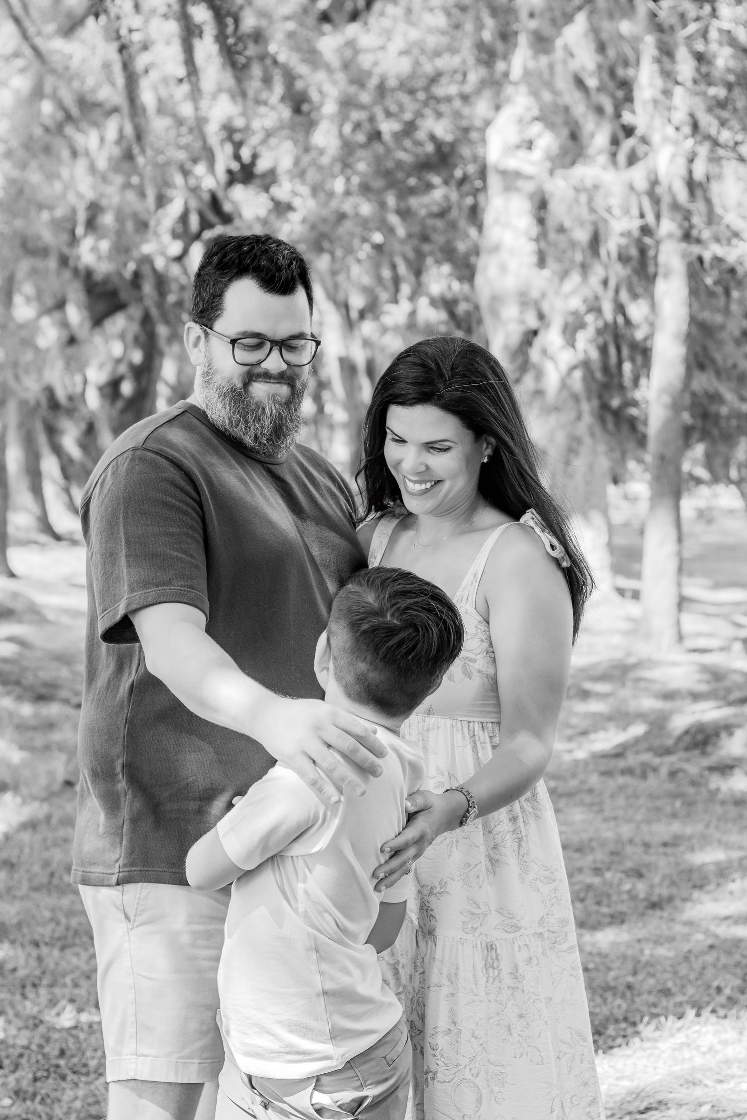 A family shares a joyful moment together outdoors in a wooded park setting.